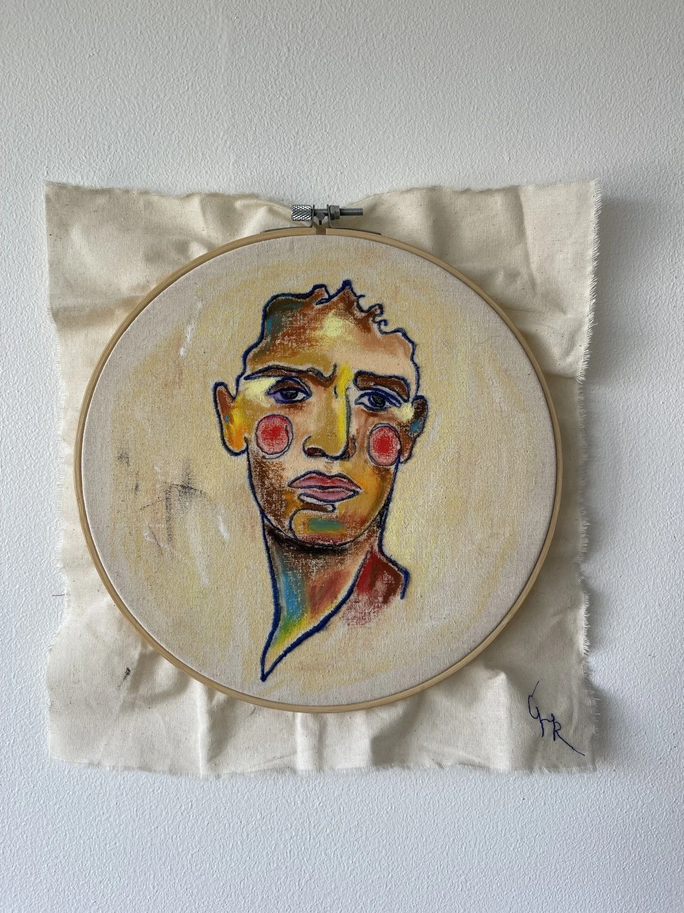 Expressive coloured face stitched and drawn in a circular embroidery hoop