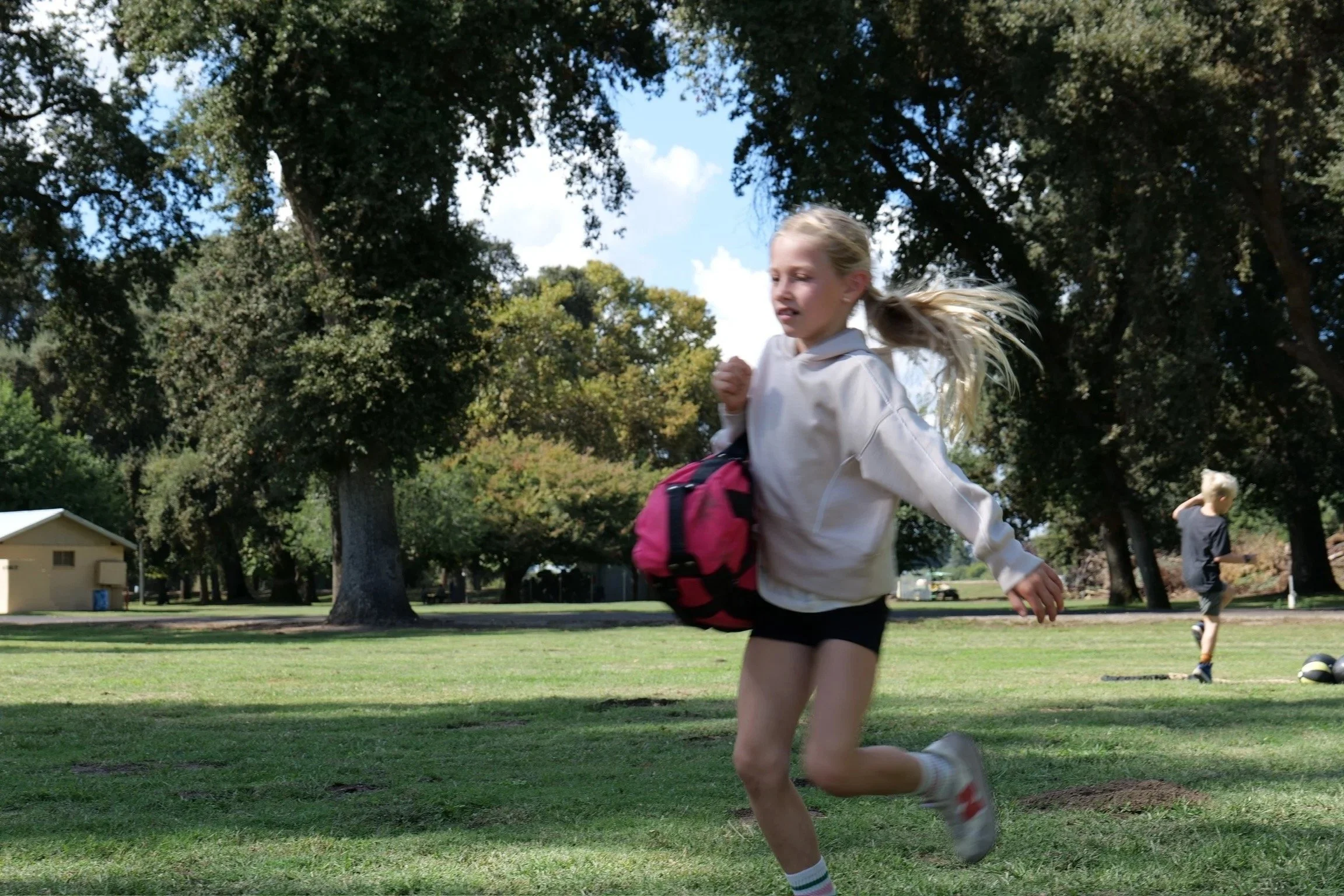 Children moving and playing together on the grass at a Fit Visalia park session
