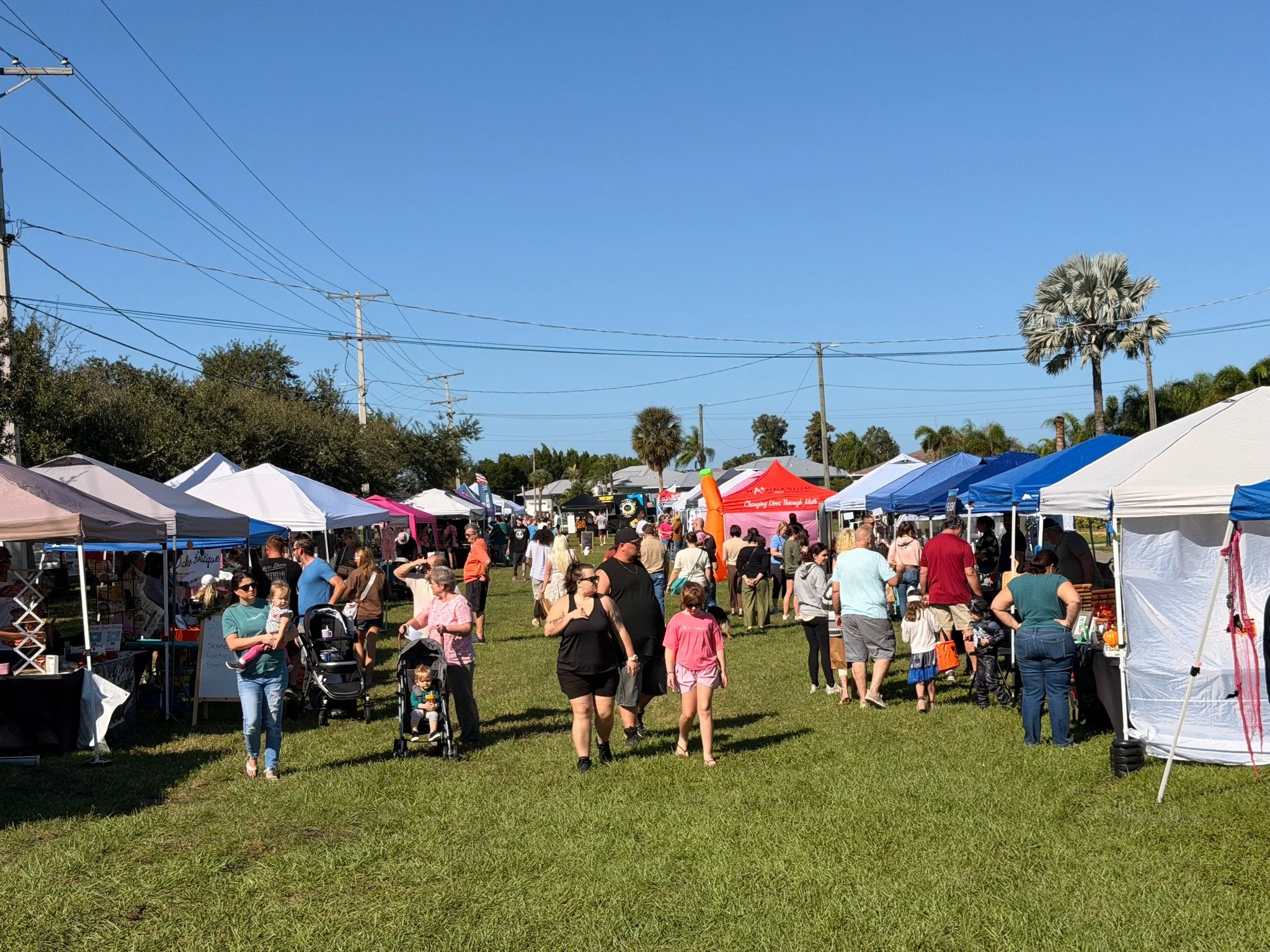 Visitors exploring local vendor tents at Apollo Beach Market