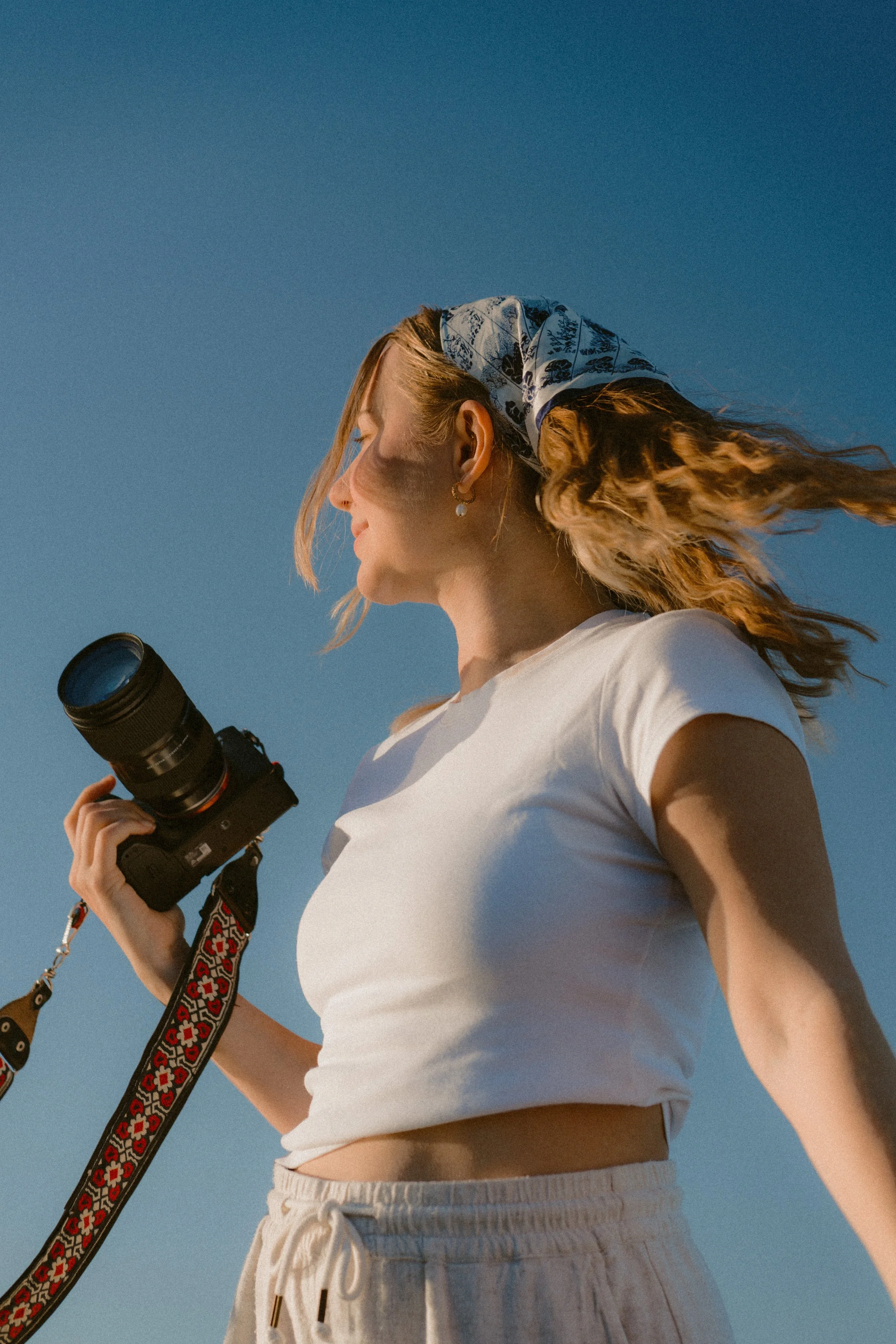 Abby holding her camera in the sunlight, with wind in her hair