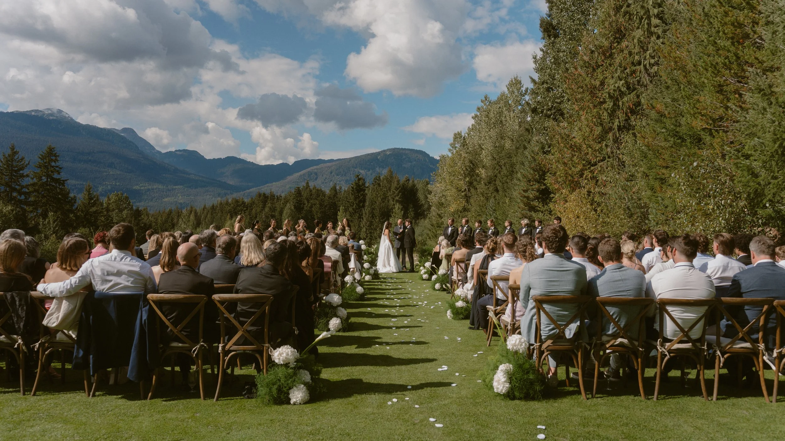 Outdoor wedding ceremony at the Fairmont in Whistler, with seated guests and mountains behind the couple