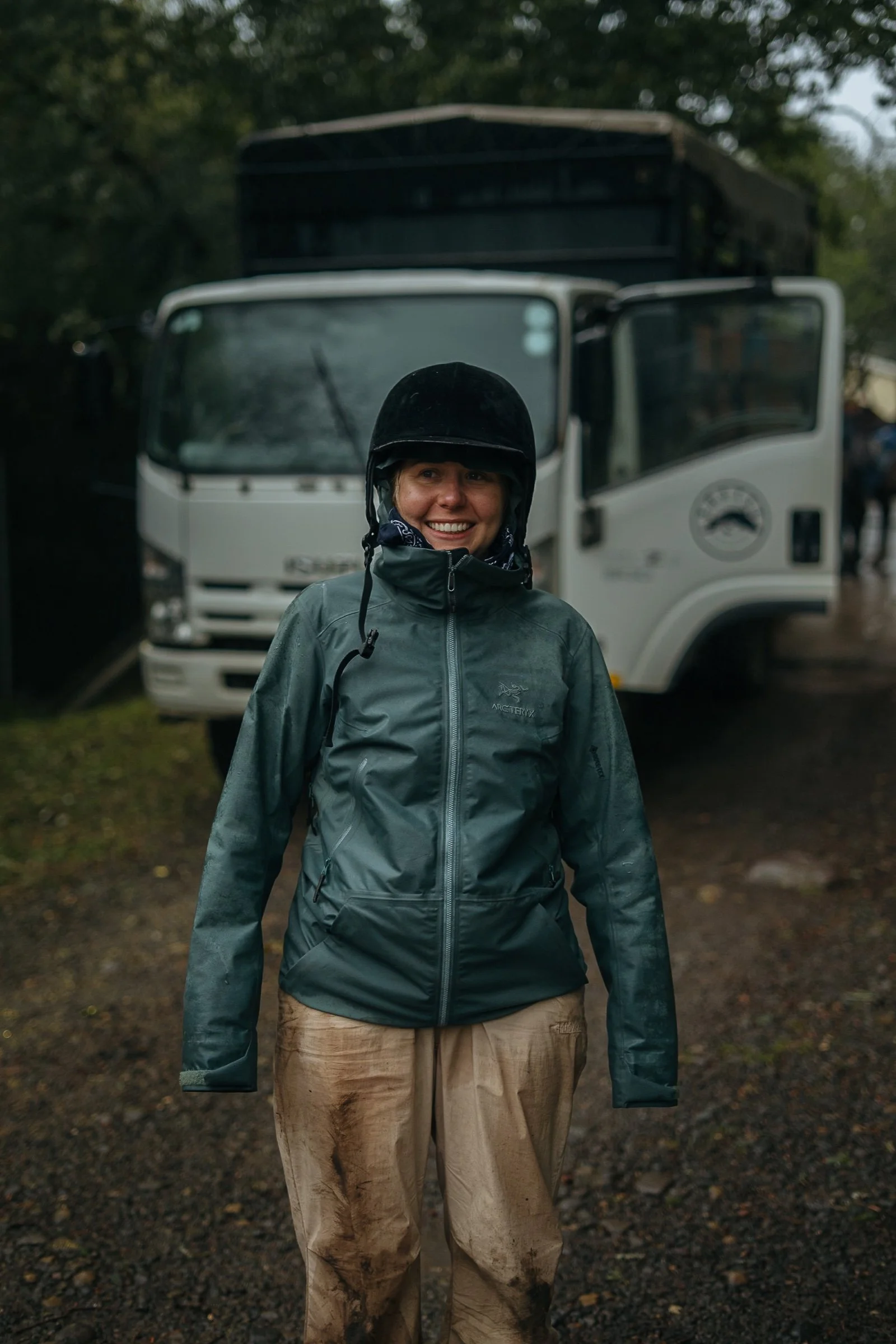 Abby grinning in her riding helmet and muddy clothes after a rainy adventure