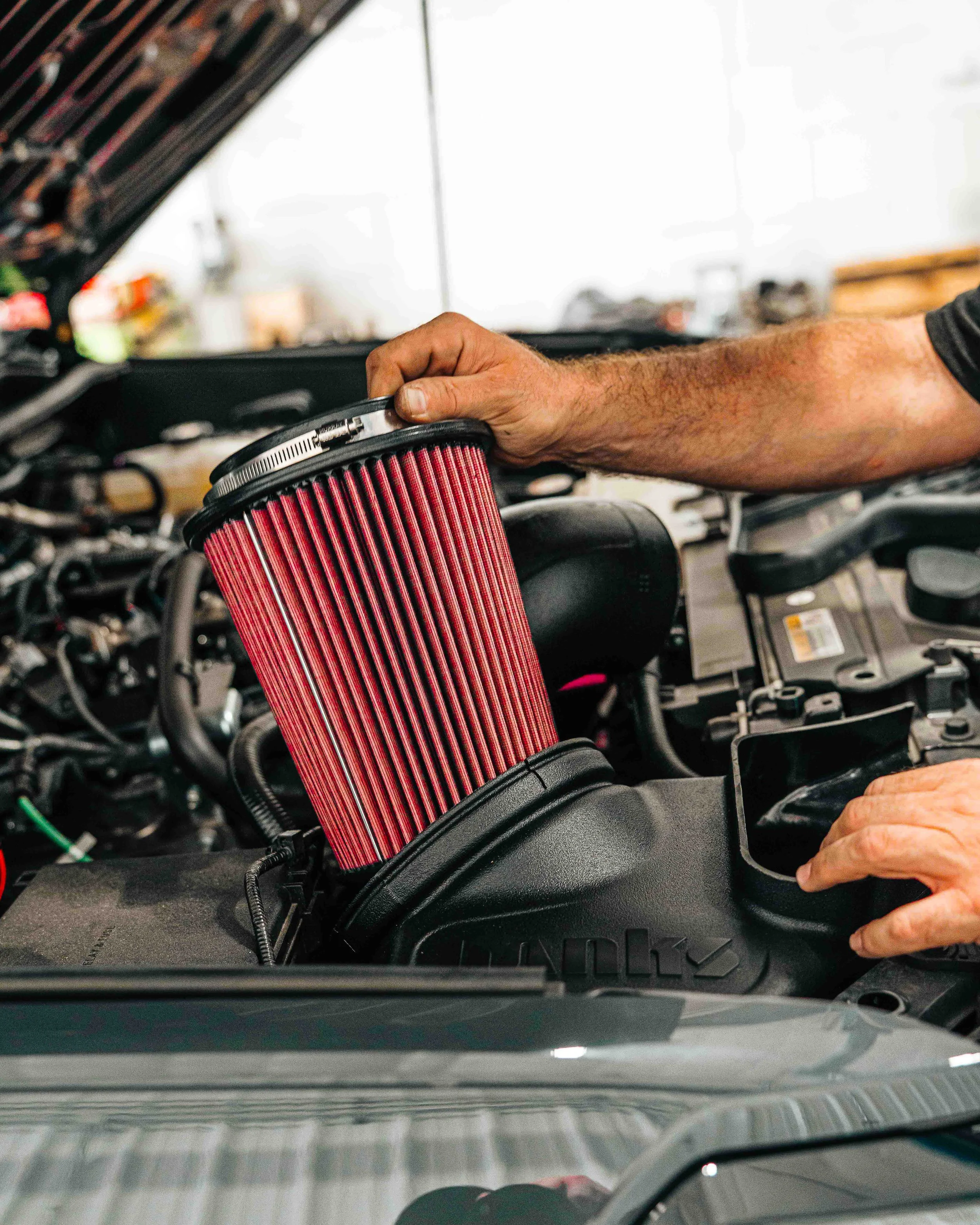 Technician installing a high-flow cold air intake filter for a performance upgrade at Xtreme Car & Truck in Bridgeville, PA