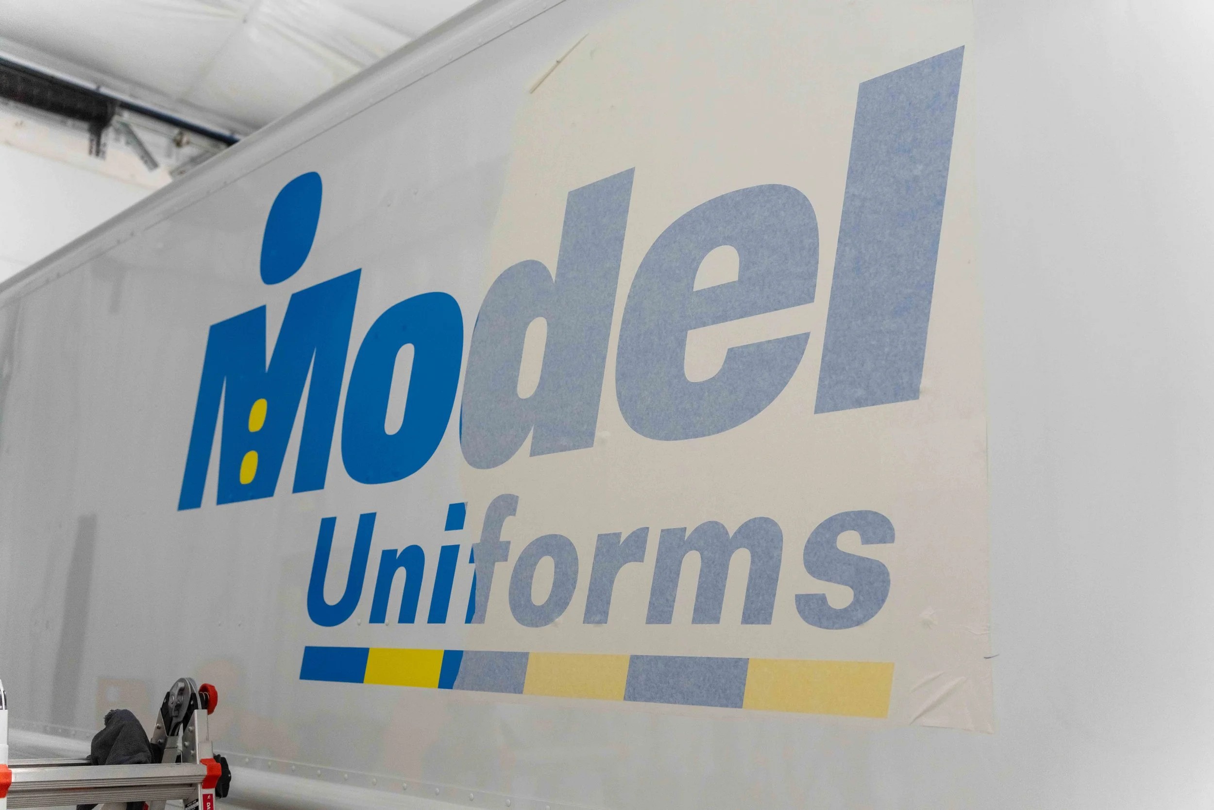 Model Uniforms rental delivery van displaying custom commercial van graphics, logo branding, and professional vinyl lettering by Xtreme Car & Truck Accessories.