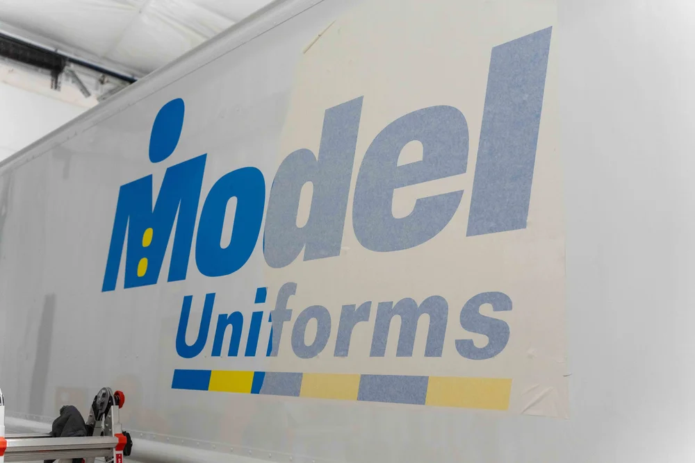 Model Uniforms rental delivery van displaying custom commercial van graphics, logo branding, and professional vinyl lettering by Xtreme Car & Truck Accessories.