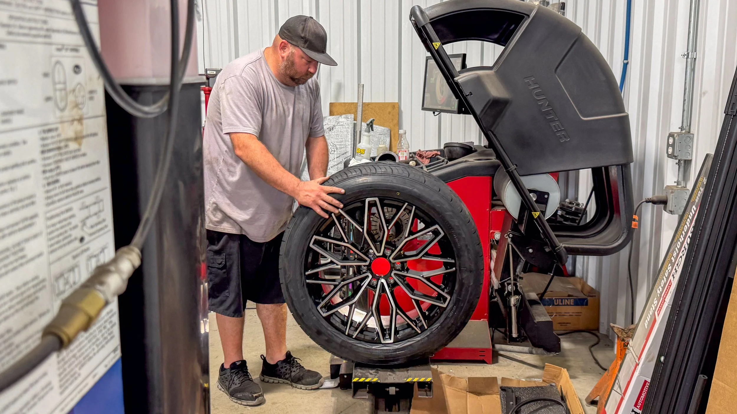 Technician loading a black and machined multi-spoke wheel with red center cap onto a Hunter balancer at Xtreme Car & Truck Accessories in Bridgeville, PA