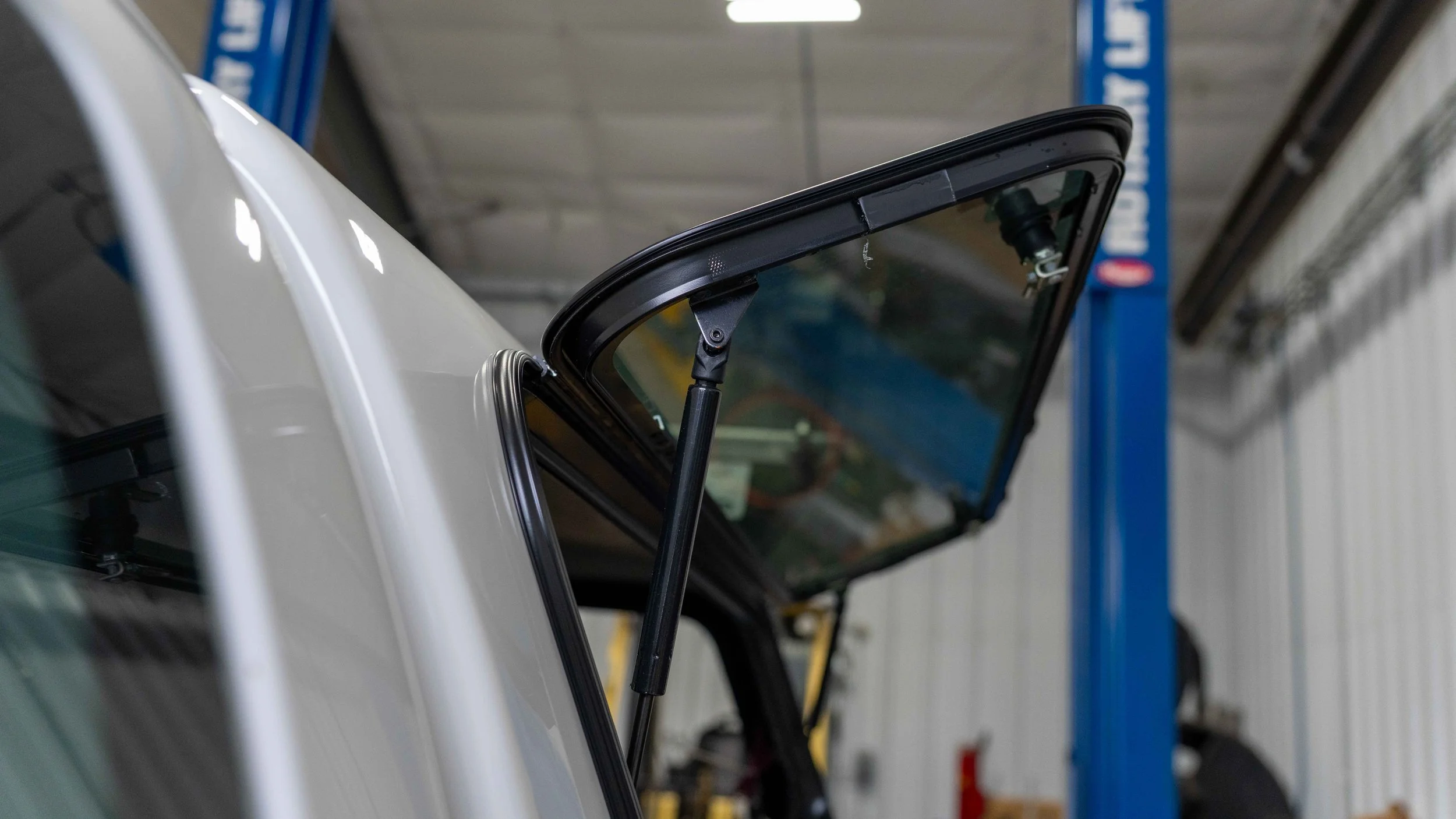 Close view of a Ranch truck cap side access window held open by a gas strut on a white Toyota Tacoma at Xtreme in Bridgeville, PA