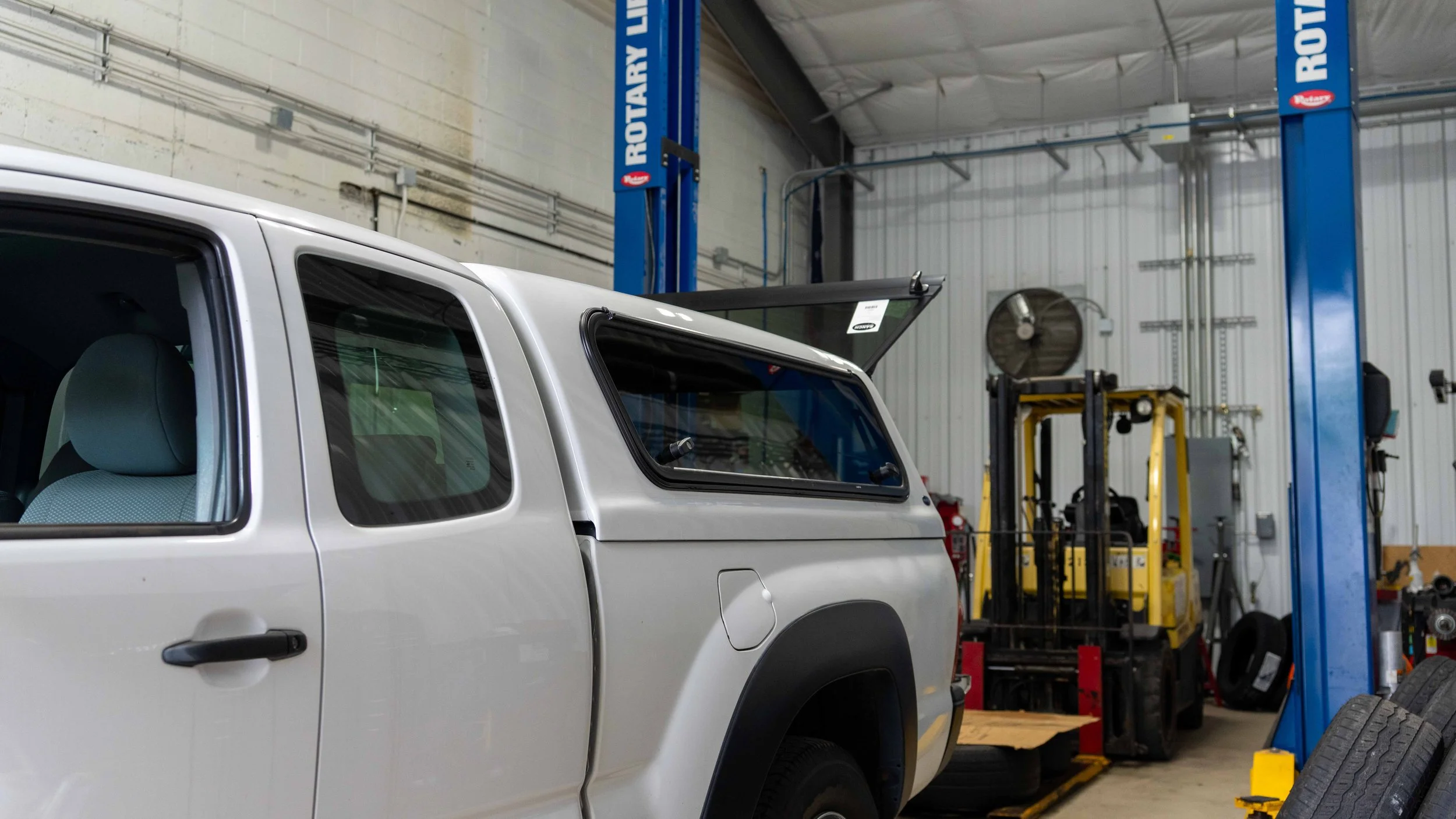White Ranch Echo truck cap installed on a Toyota Tacoma with the side window propped open inside the Xtreme install bay in Bridgeville, PA