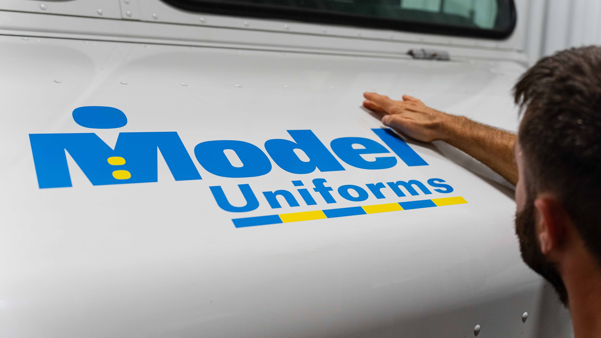 Model Uniforms rental delivery van during custom vinyl graphics work at Xtreme Car & Truck Accessories for professional commercial fleet branding.