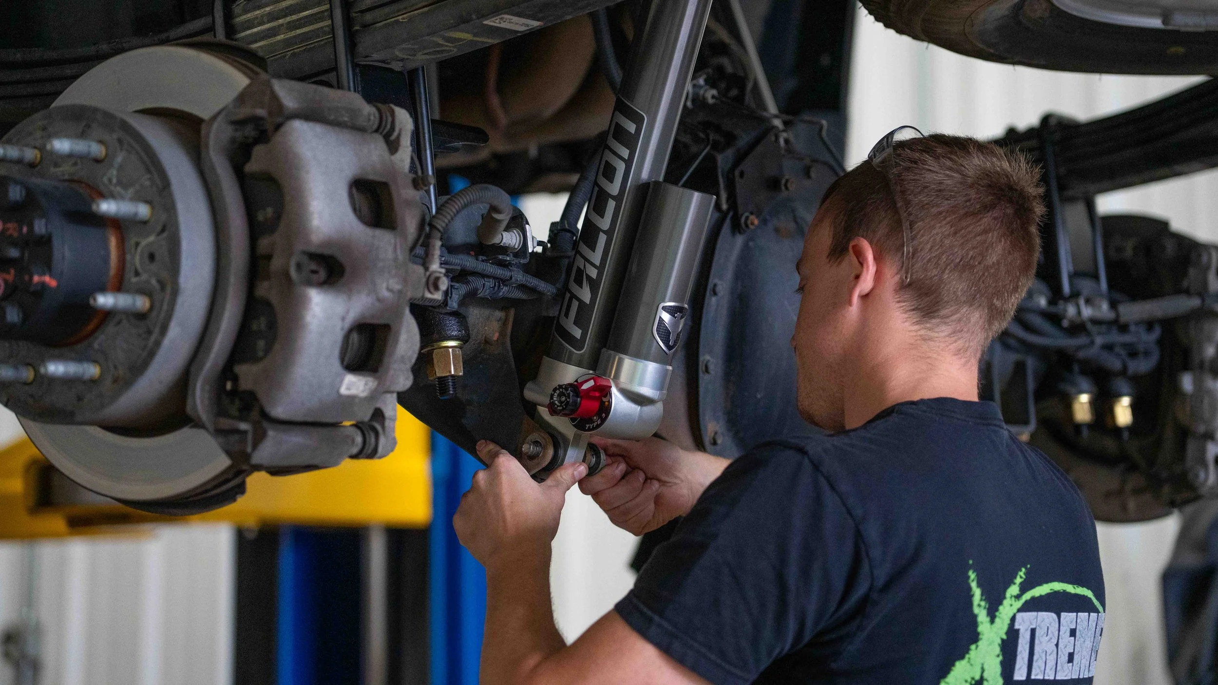 Technician installing Falcon 3.3 shocks on a GMC Sierra ReadyLIFT 6-inch MAX3 suspension lift at Xtreme Car & Truck in Bridgeville, PA.