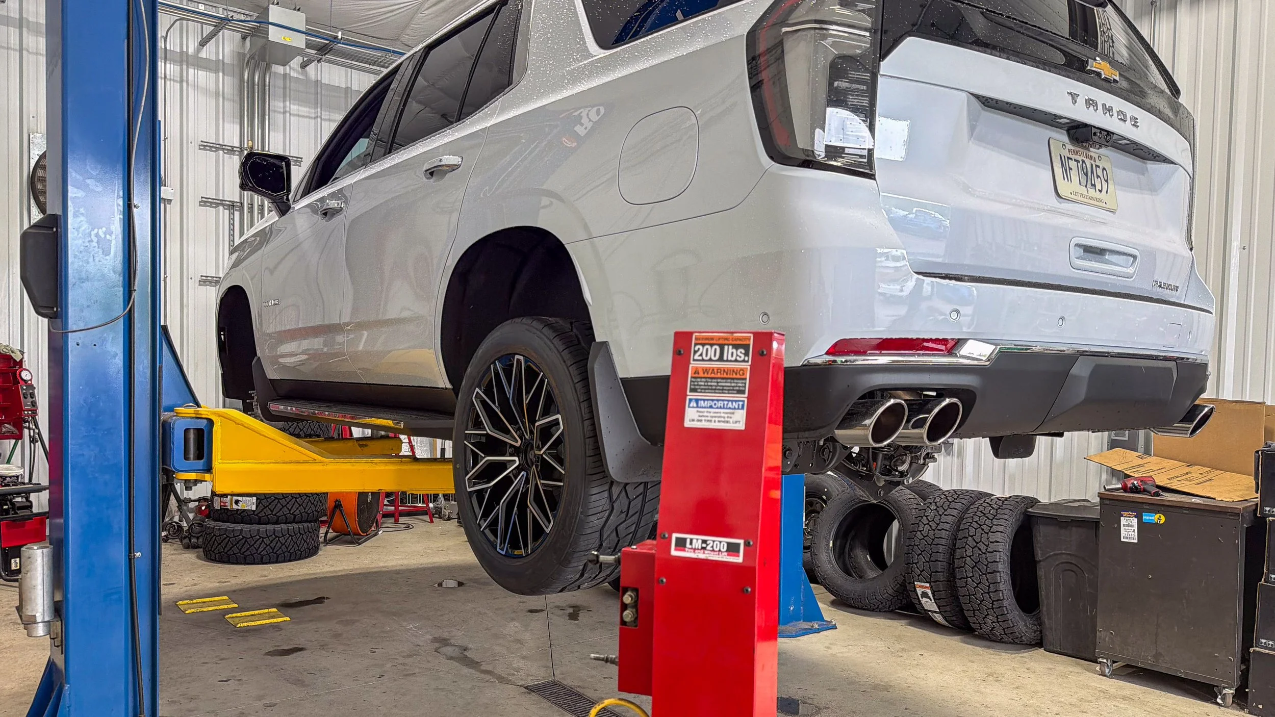 Chevrolet Tahoe on a shop lift with quad exhaust tips, showing performance exhaust styling at Xtreme Car & Truck in Bridgeville, PA