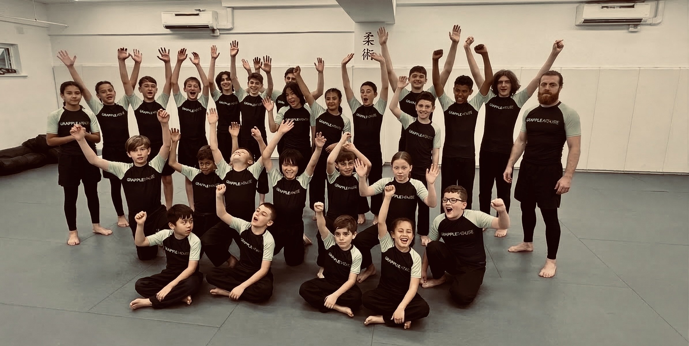 Coach Keith Vartanian with Grapple House students on the mats