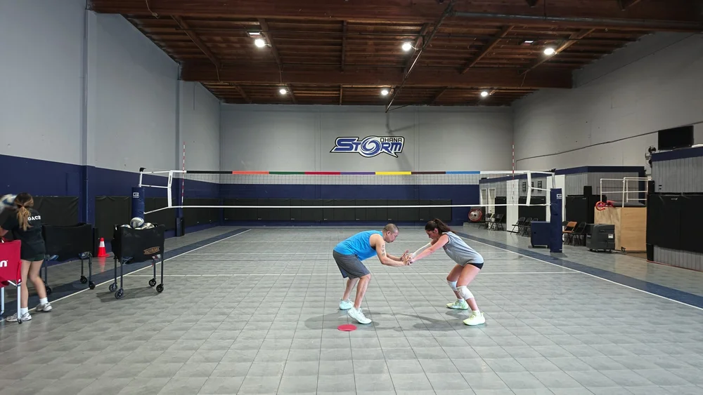 Coach Chris demonstrates the supported ready position with an athlete on court.