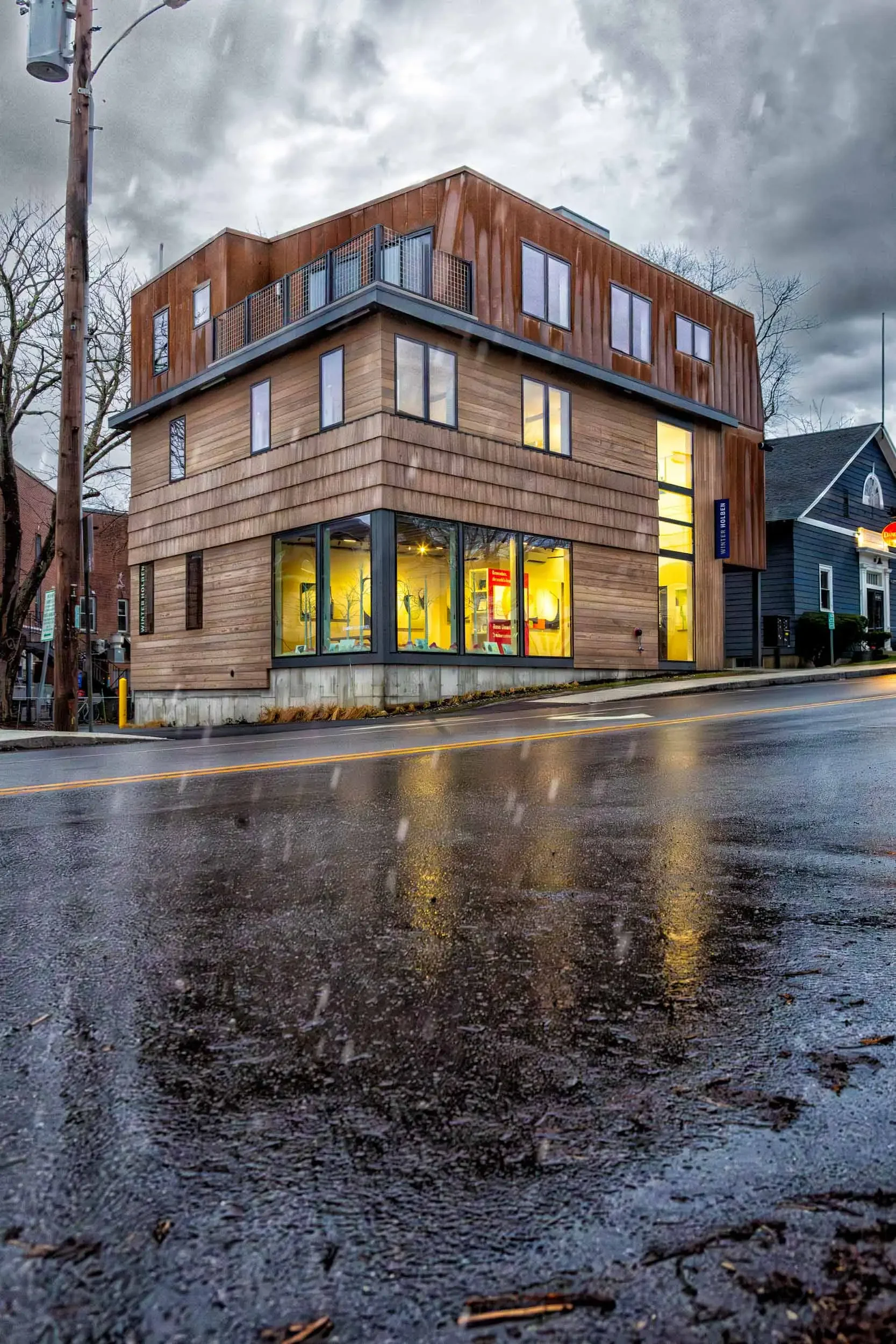 Winter Holben’s contemporary studio building at a street corner after rain