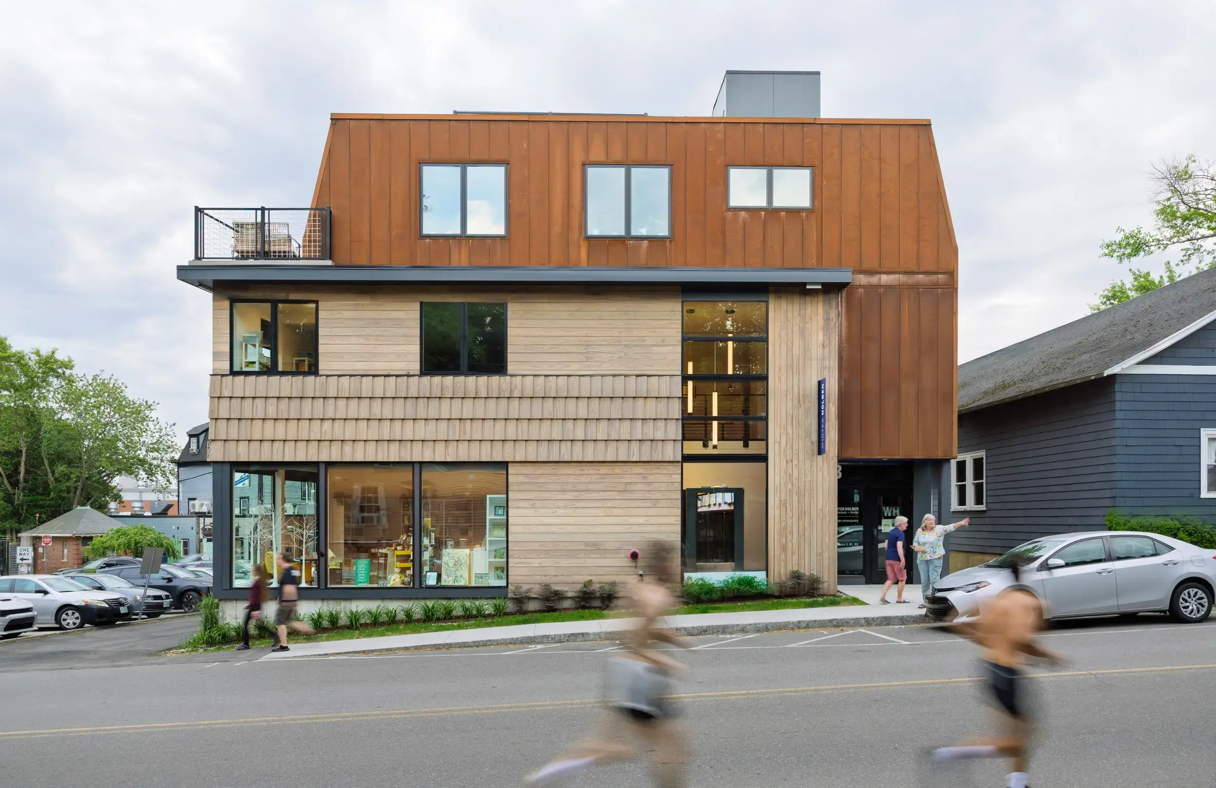 Winter Holben’s 3 Walker building with copper-toned cladding and wood siding, with runners passing in the foreground