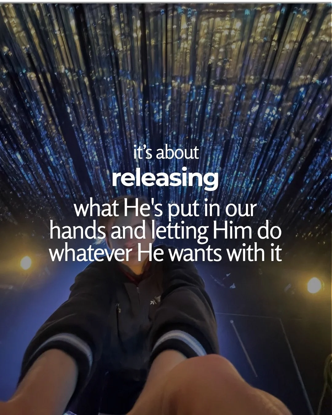 A young man reaches toward the camera from below a ceiling of hanging strands of blue and gold lights. Text: it’s about releasing what He's put in our hands and letting Him do whatever He wants with it