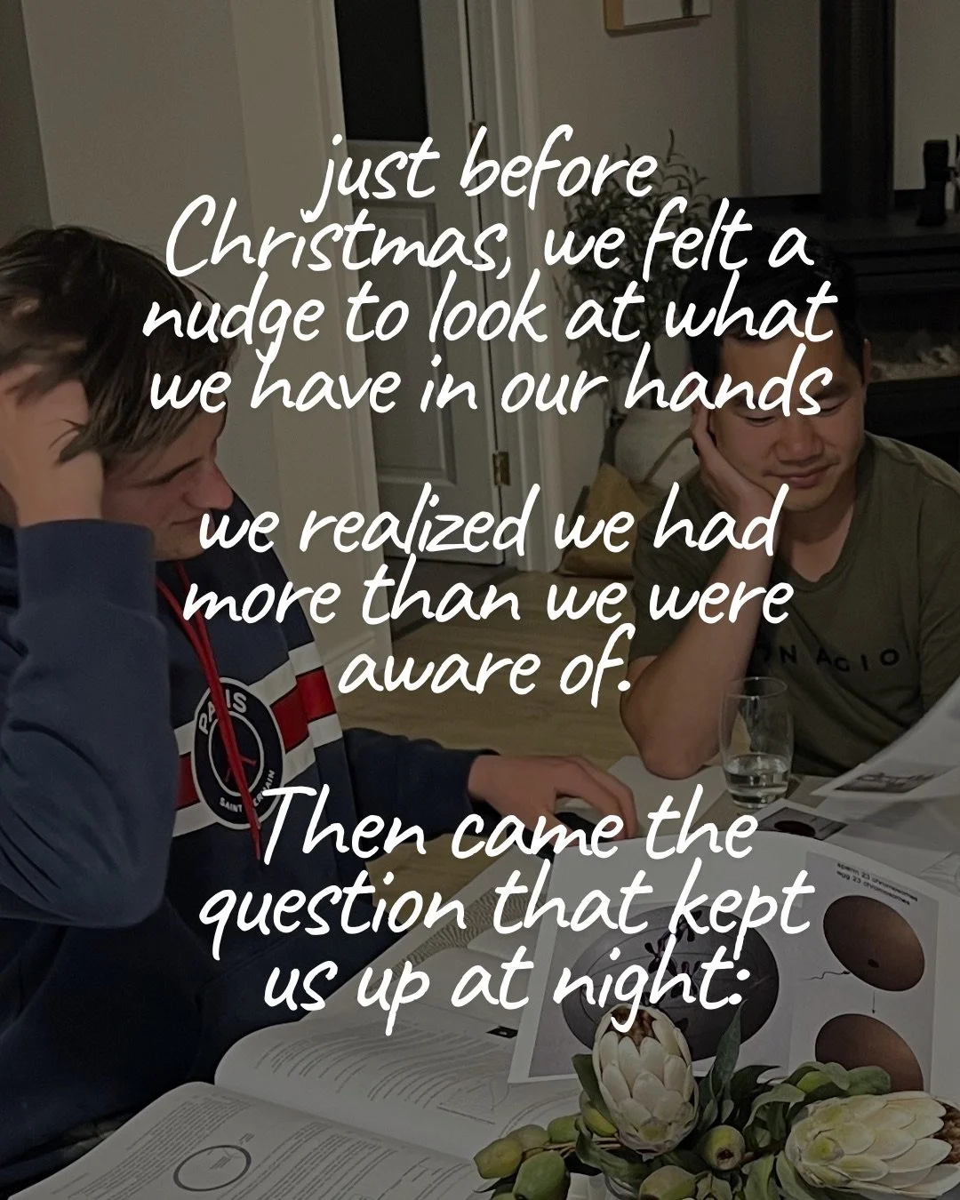 Two young men seated at a table covered with open books and papers and a vase of protea flowers, one resting his head in his hand. Text: just before Christmas, we felt a nudge to look at what we have in our hands we realized we had more than we were aware of. Then came the question that kept us up at night: