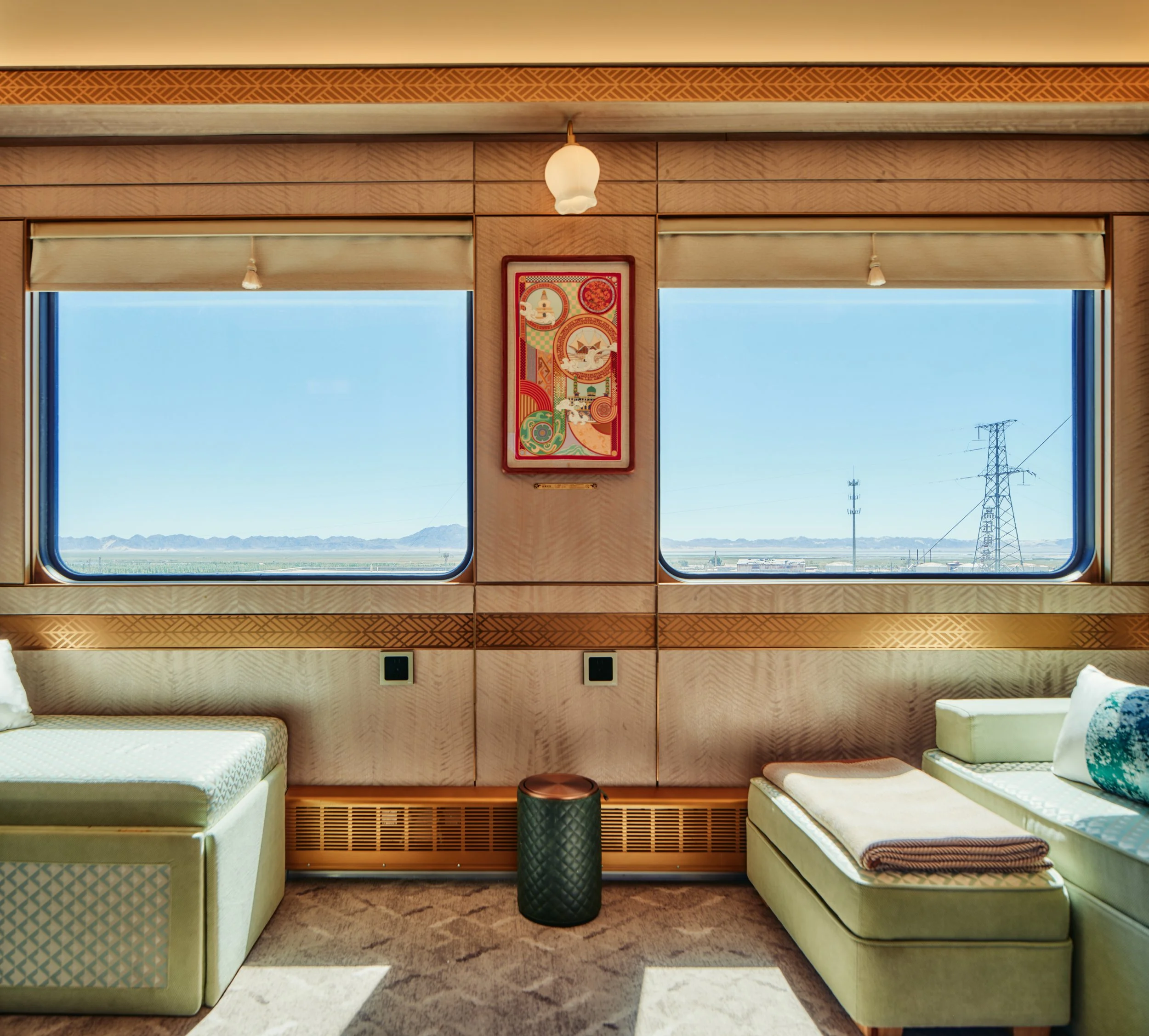 Deluxe Suite (Family) with two windows, framed artwork and mint-green seating facing the desert