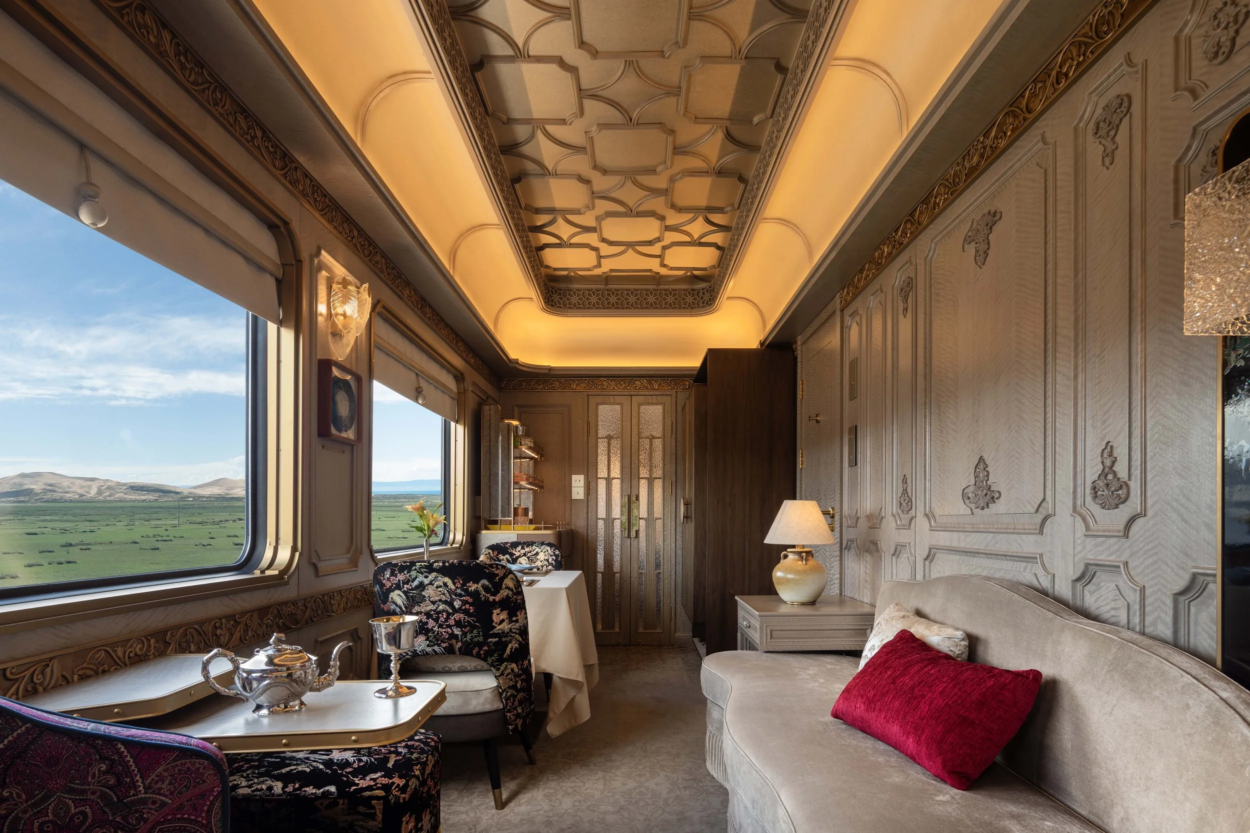 Grand Suite living area with a sofa, floral armchairs and a silver tea set beside wide windows