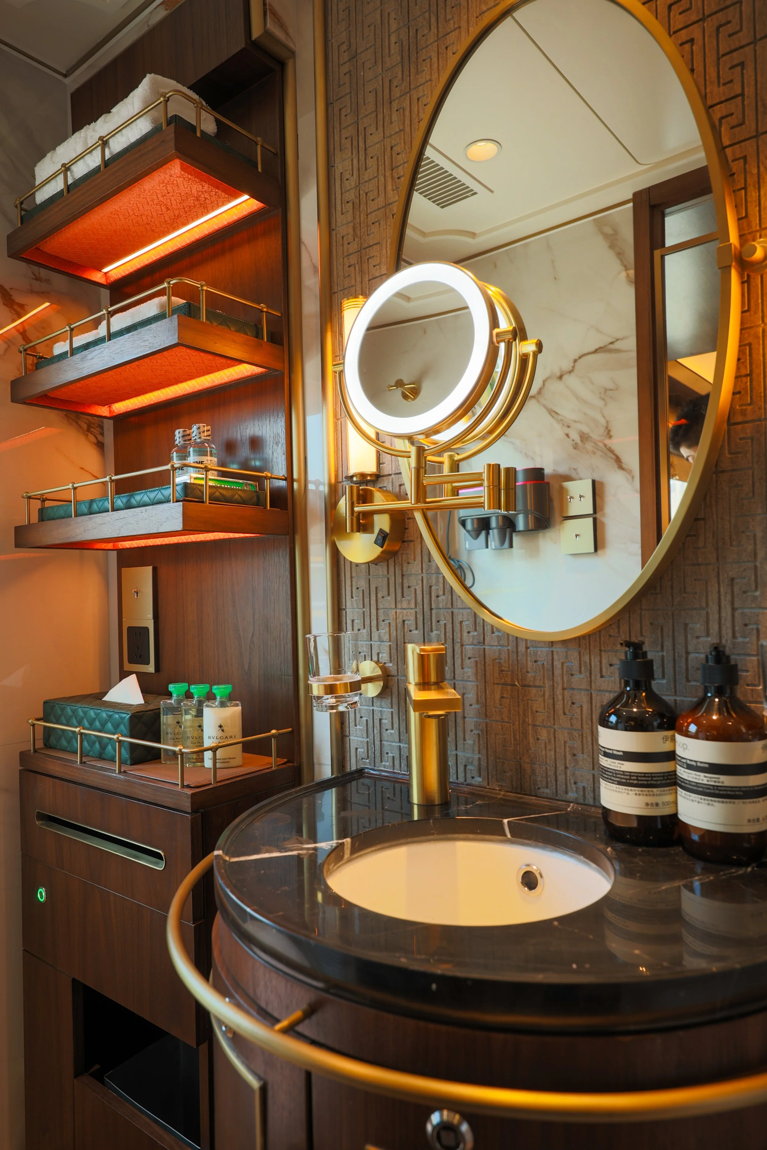 Deluxe Suite (King) bathroom with a round marble washbasin, oval mirror and Aesop toiletries