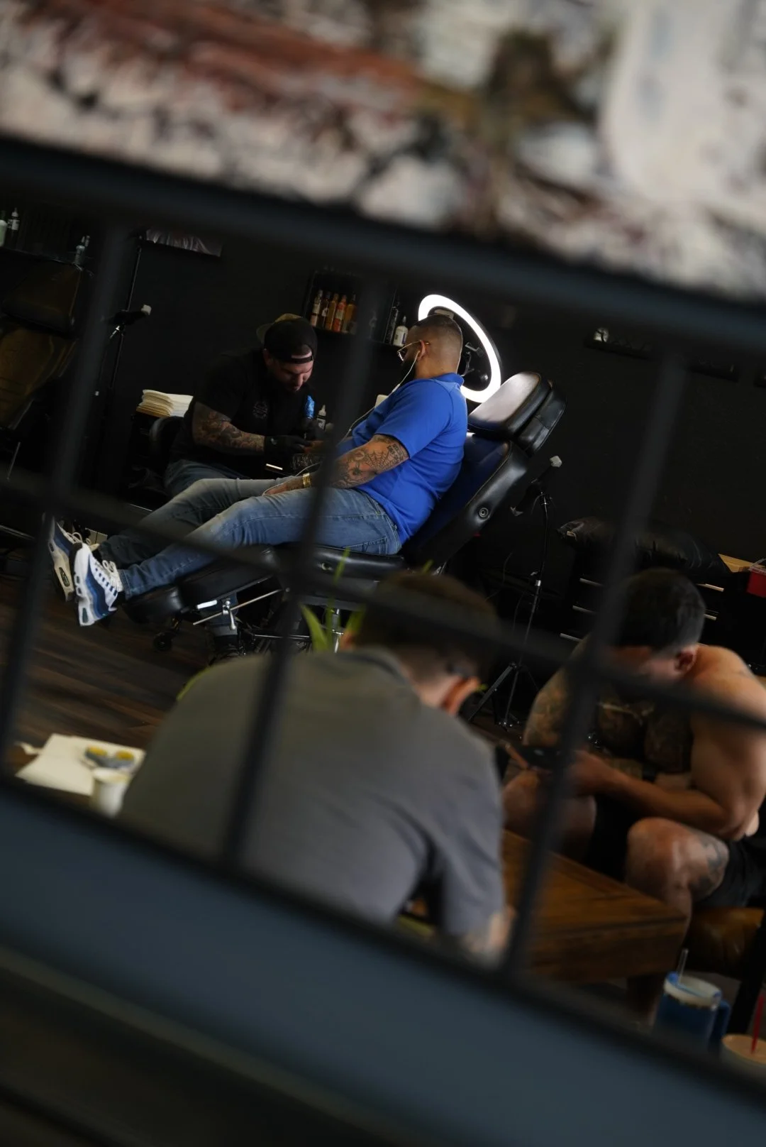 A tattoo session reflected in a studio mirror