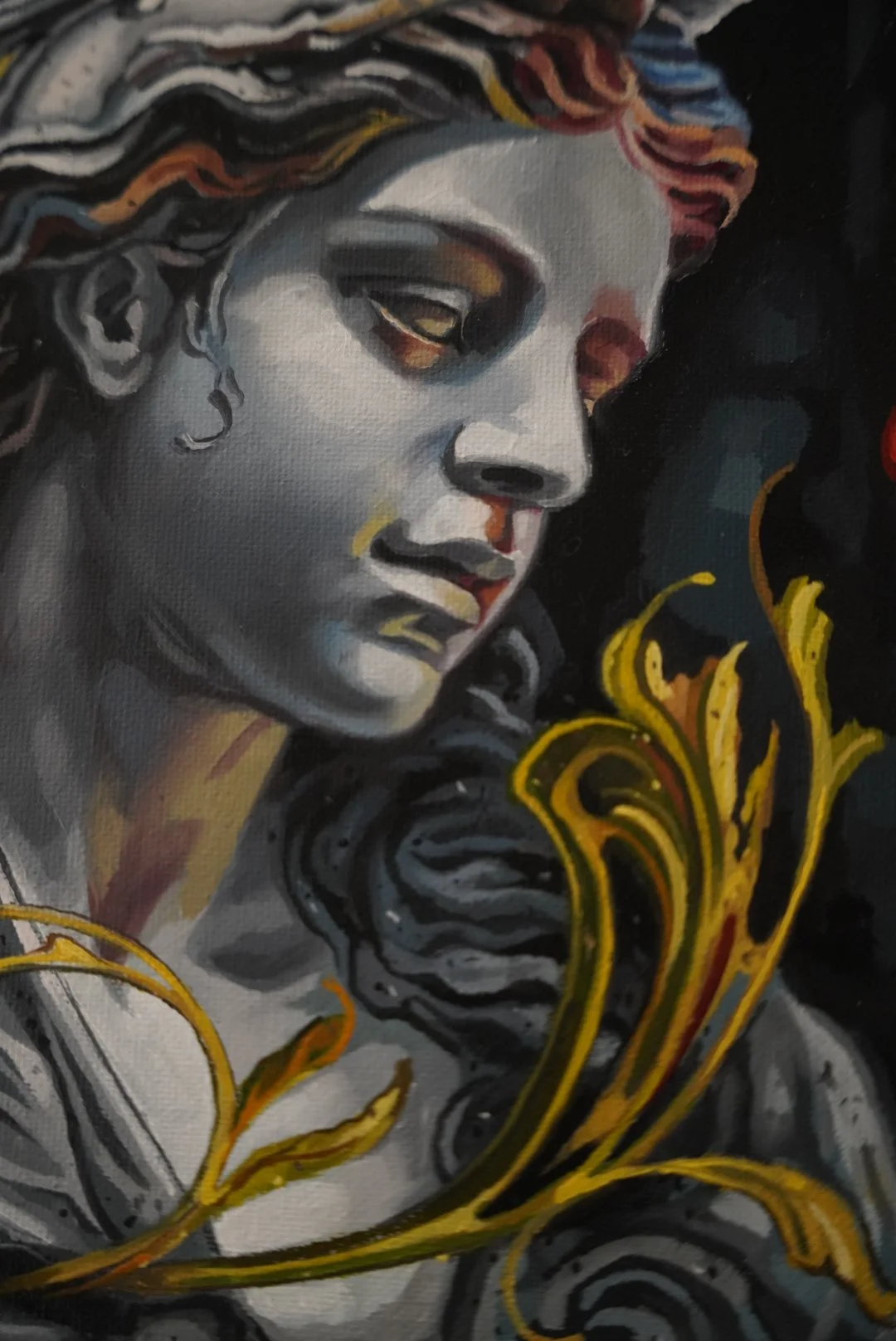 Detail of a painted classical face in cool gray tones beside golden ornamental foliage.