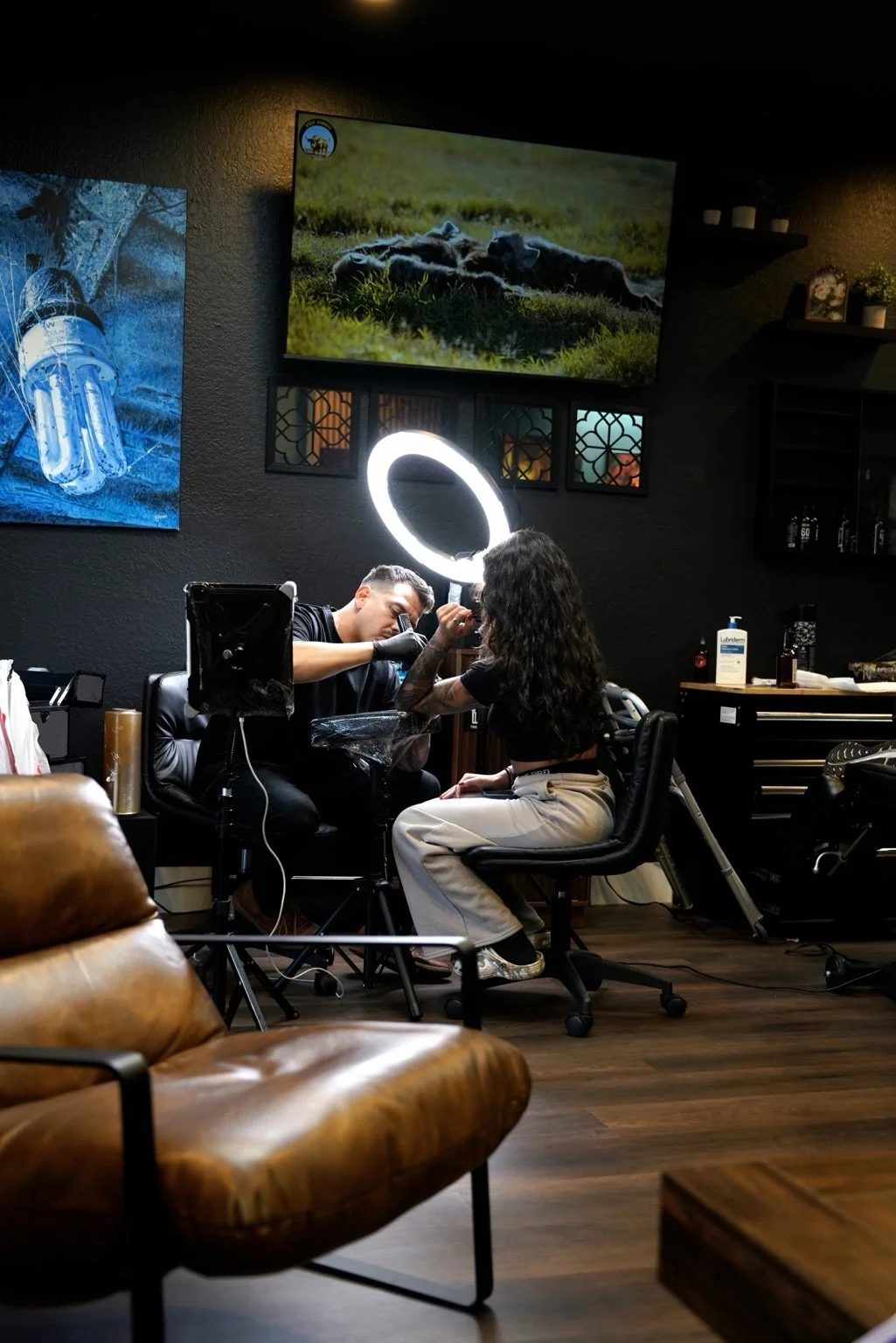 Tattoo artist at work, viewed from the studio’s leather seating area