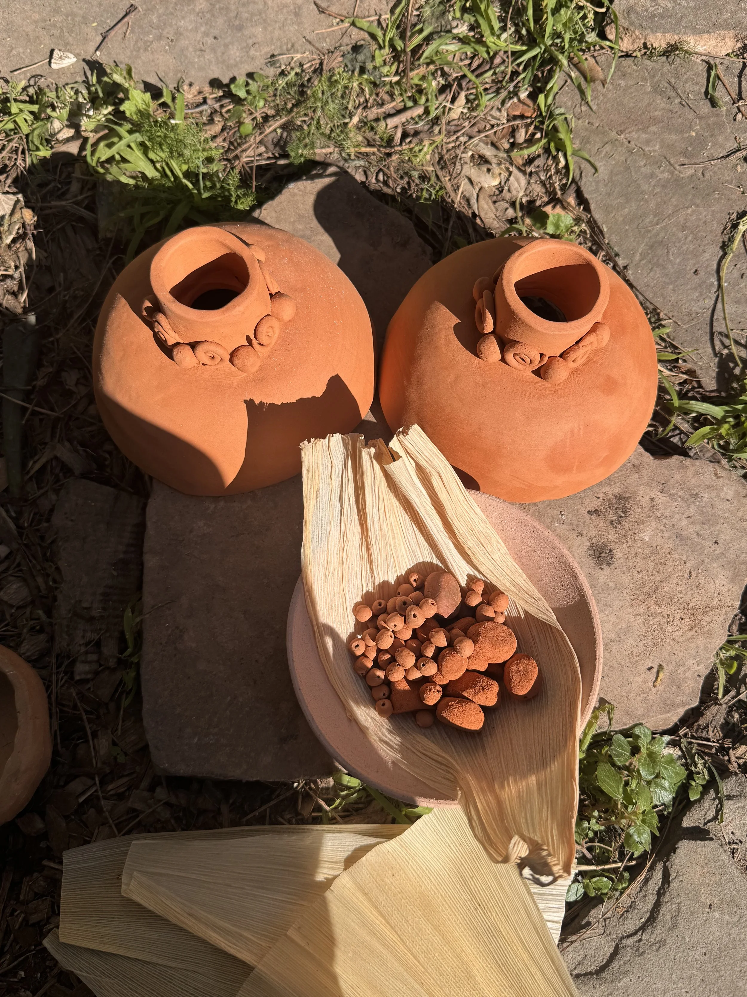 Terracotta vessels with spiral coil details, beads in a bowl with corn husks