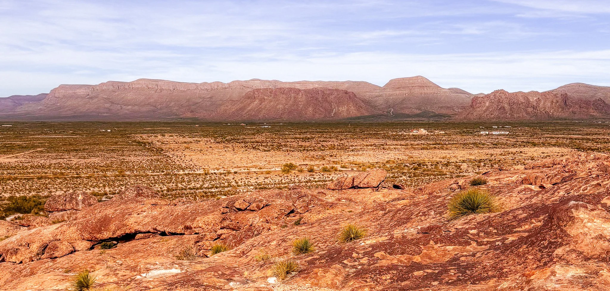 Desert mountain ridge in golden light under a deep blue sky, a small moon above