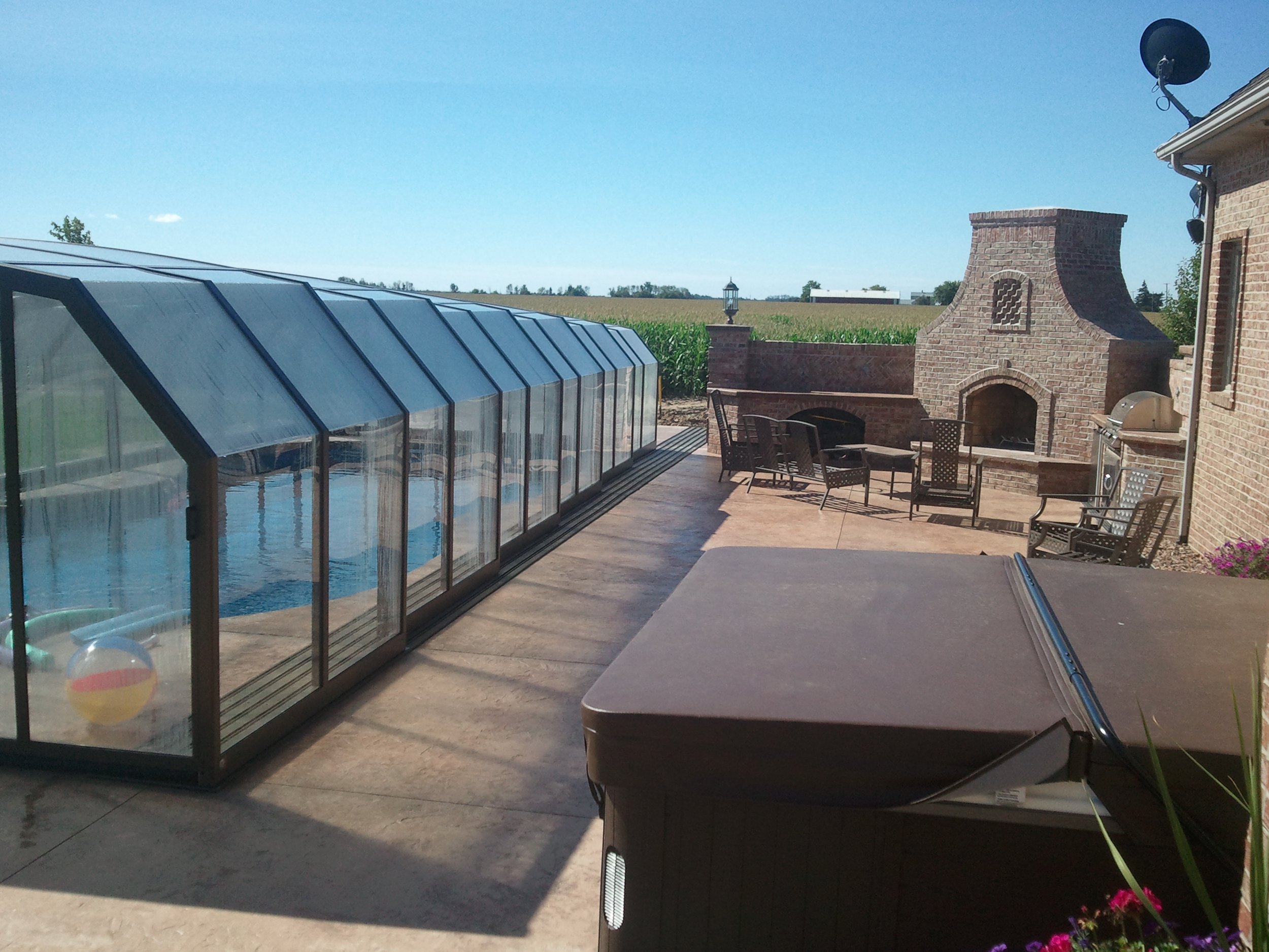 Arched retractable pool enclosure over a backyard pool, perfect for entertaining