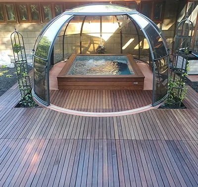Retractable hot tub enclosure with clear dome over a backyard spa