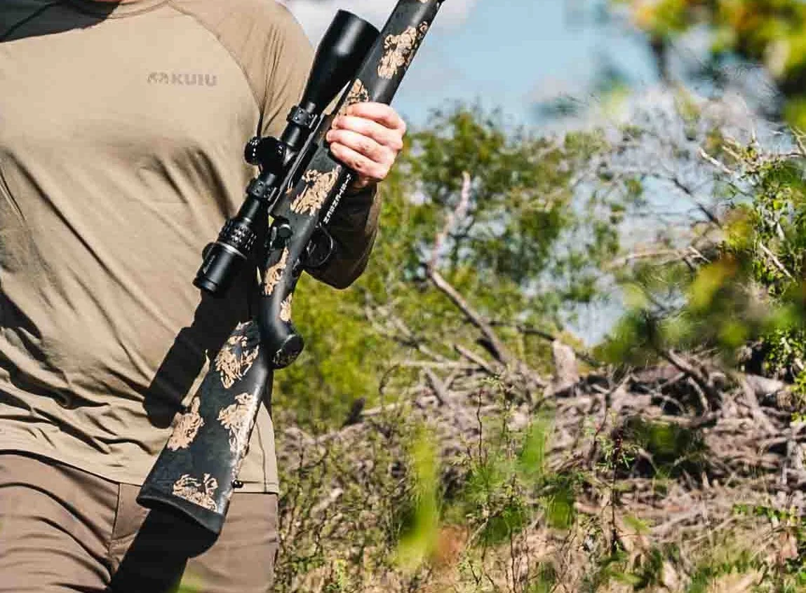 Hunter carrying a Christensen Arms rifle through the brush in Texas