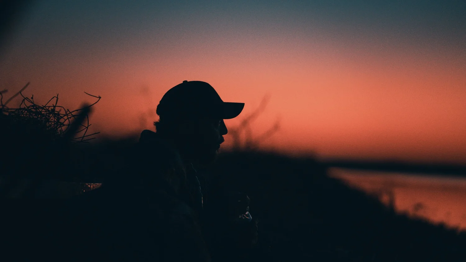 Hunter silhouetted against an orange sunset