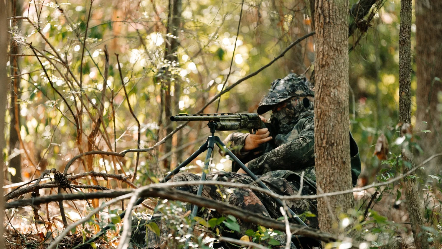 Turkey hunter in camo behind a shotgun on a Spartan tripod