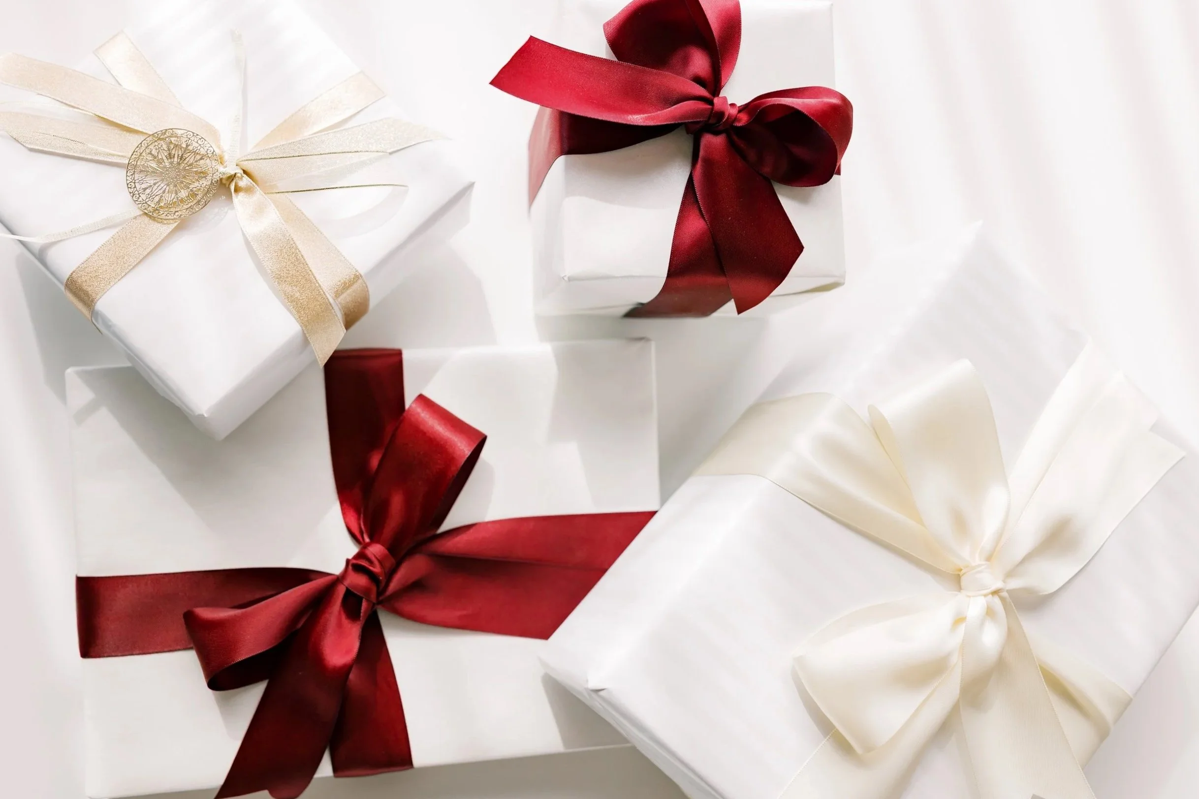 White gift boxes tied with red, cream, and gold bows