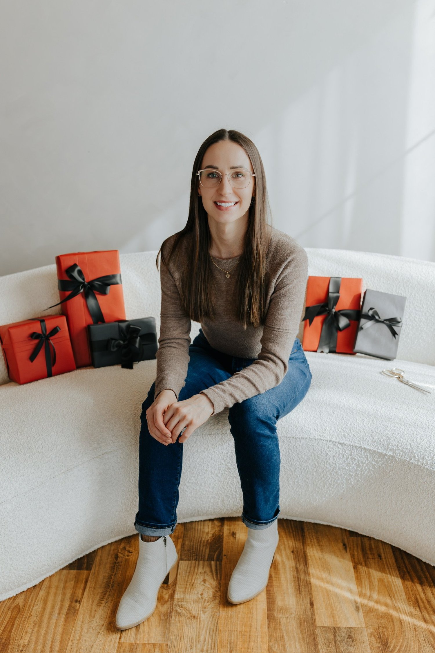 Breanna, founder of Neatly Wrapped Co., seated with wrapped gifts