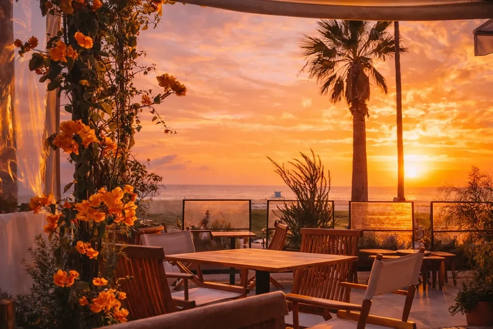 A patio table at Fig Tree looking out to the ocean at sunset