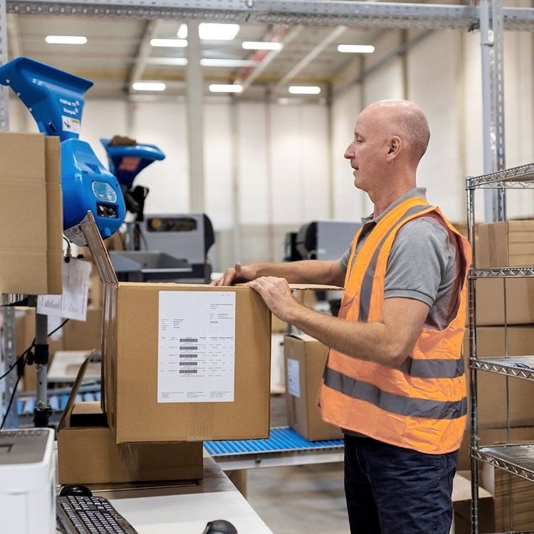 Warehouse worker packing and labelling a box for dispatch