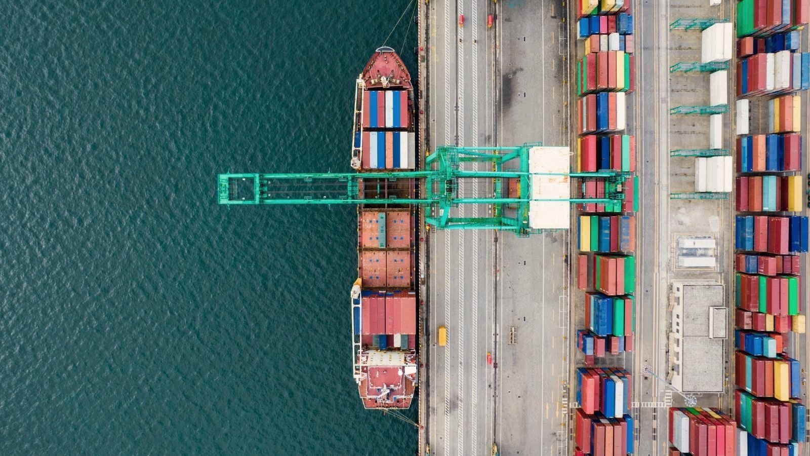Aerial view of a container ship alongside a port quay being loaded by crane