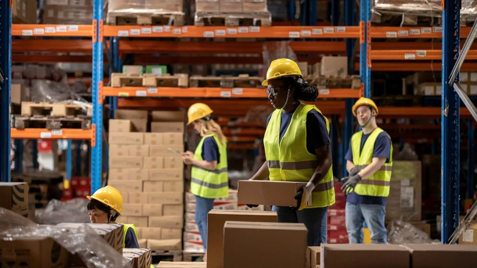 Warehouse team handling stock between orange pallet racking