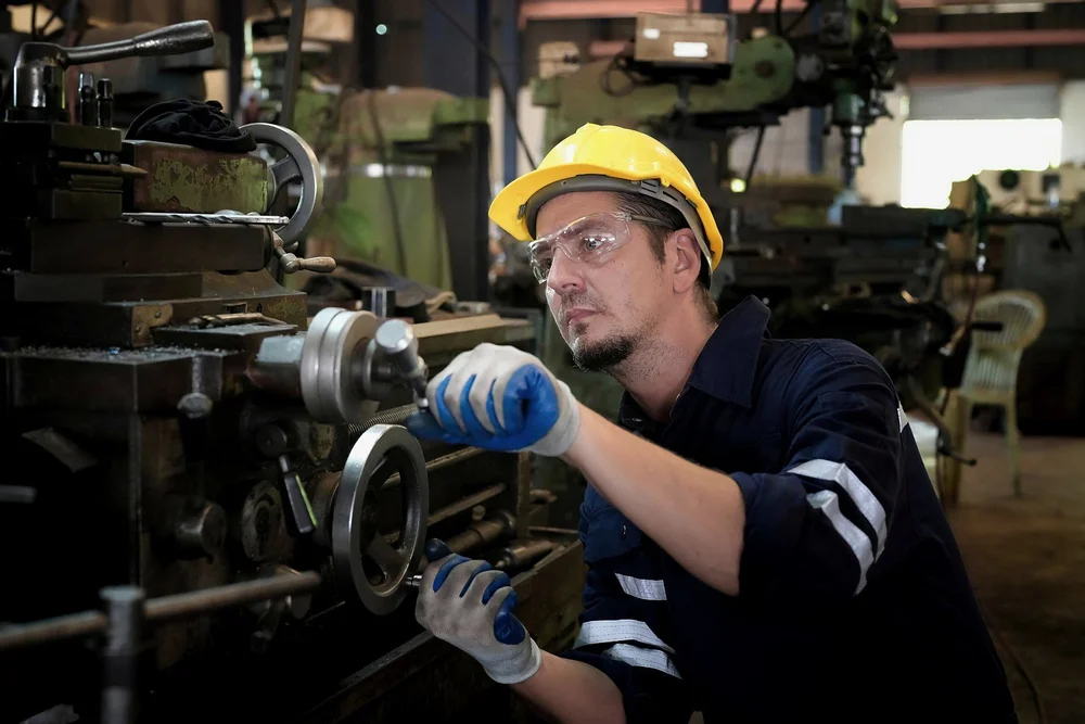 Machinist adjusting a lathe in a manufacturing workshop