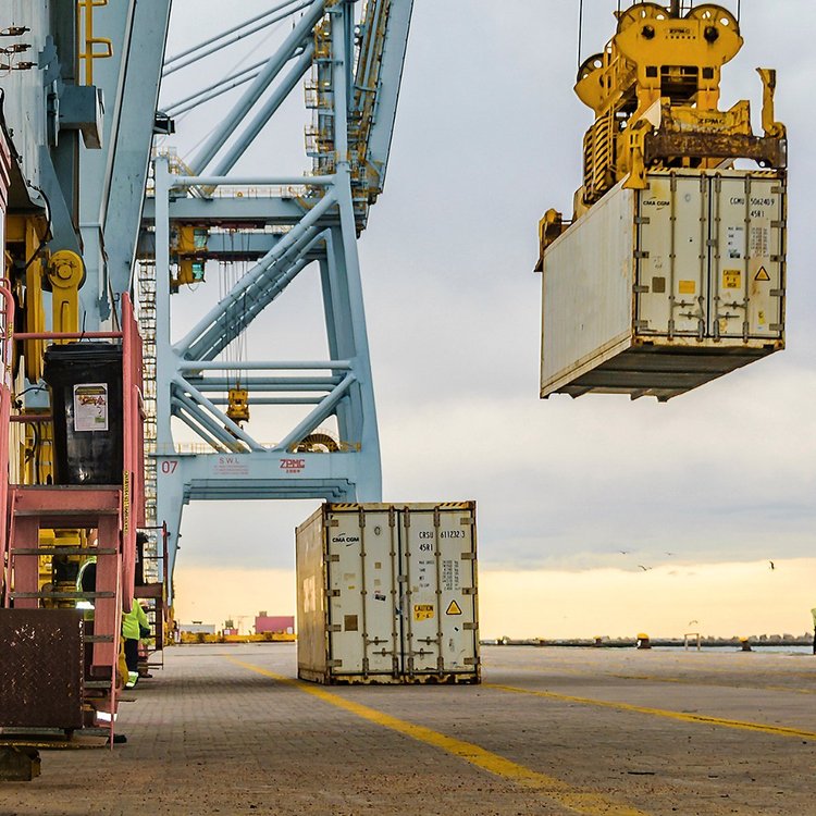Container being lifted by crane at a port quay for export