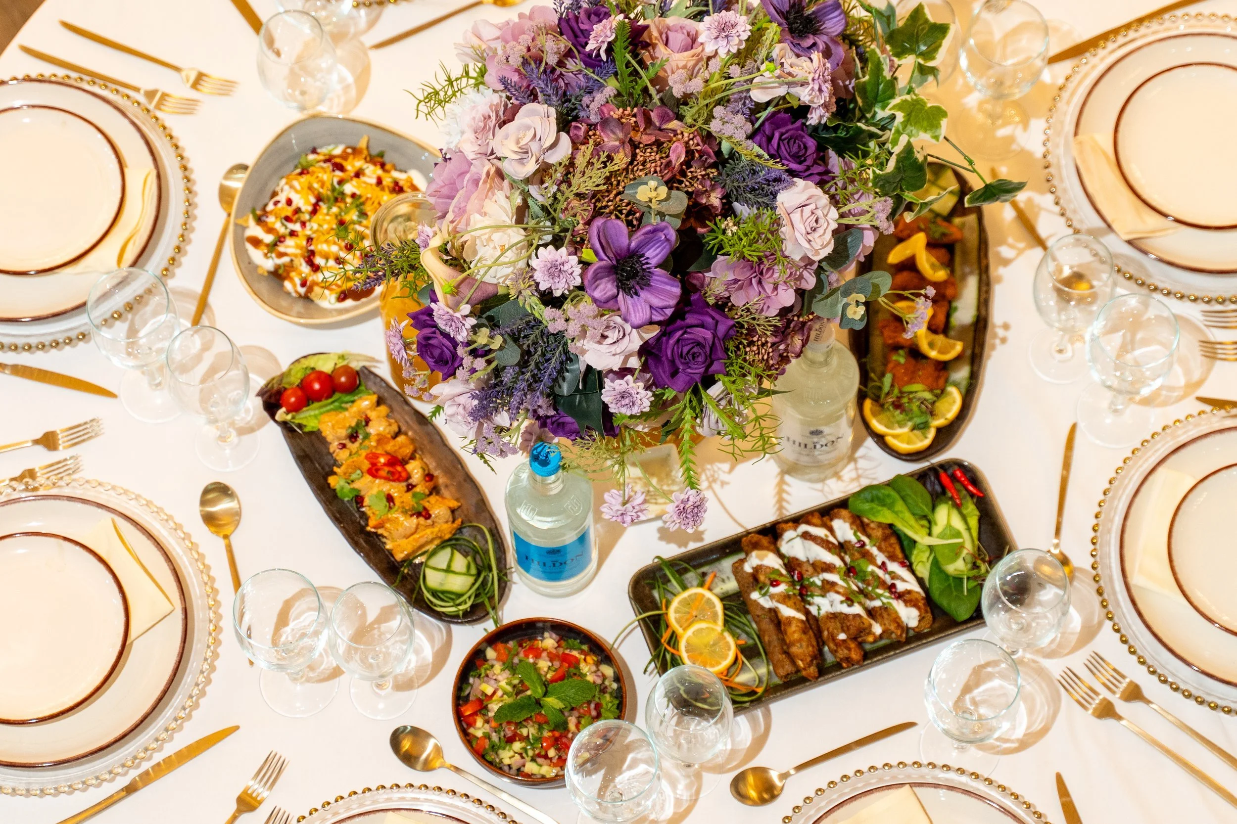 A Pakistani catering spread arranged around flowers and table settings