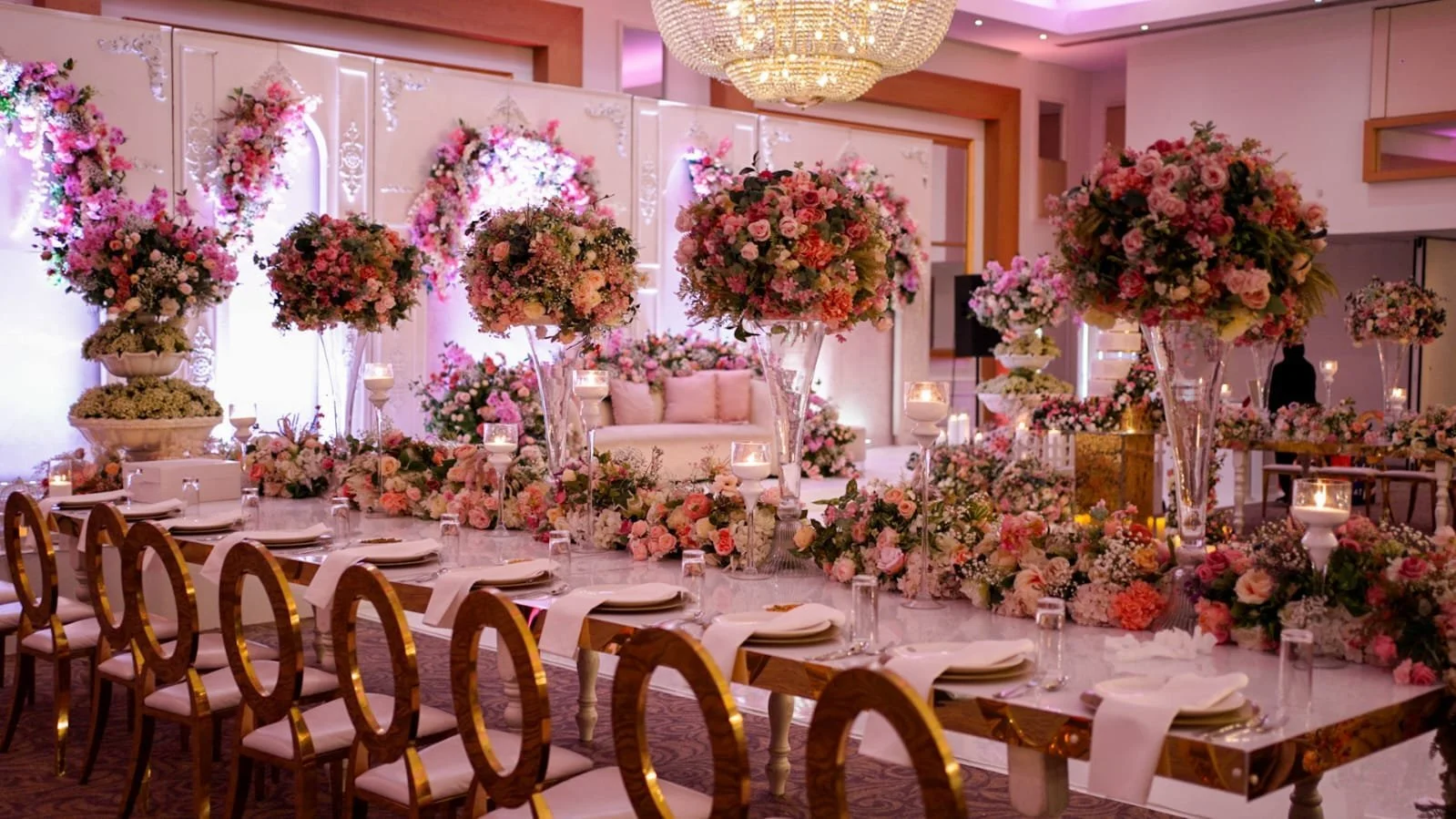 Pink floral centrepieces and dressed tables in a reception room