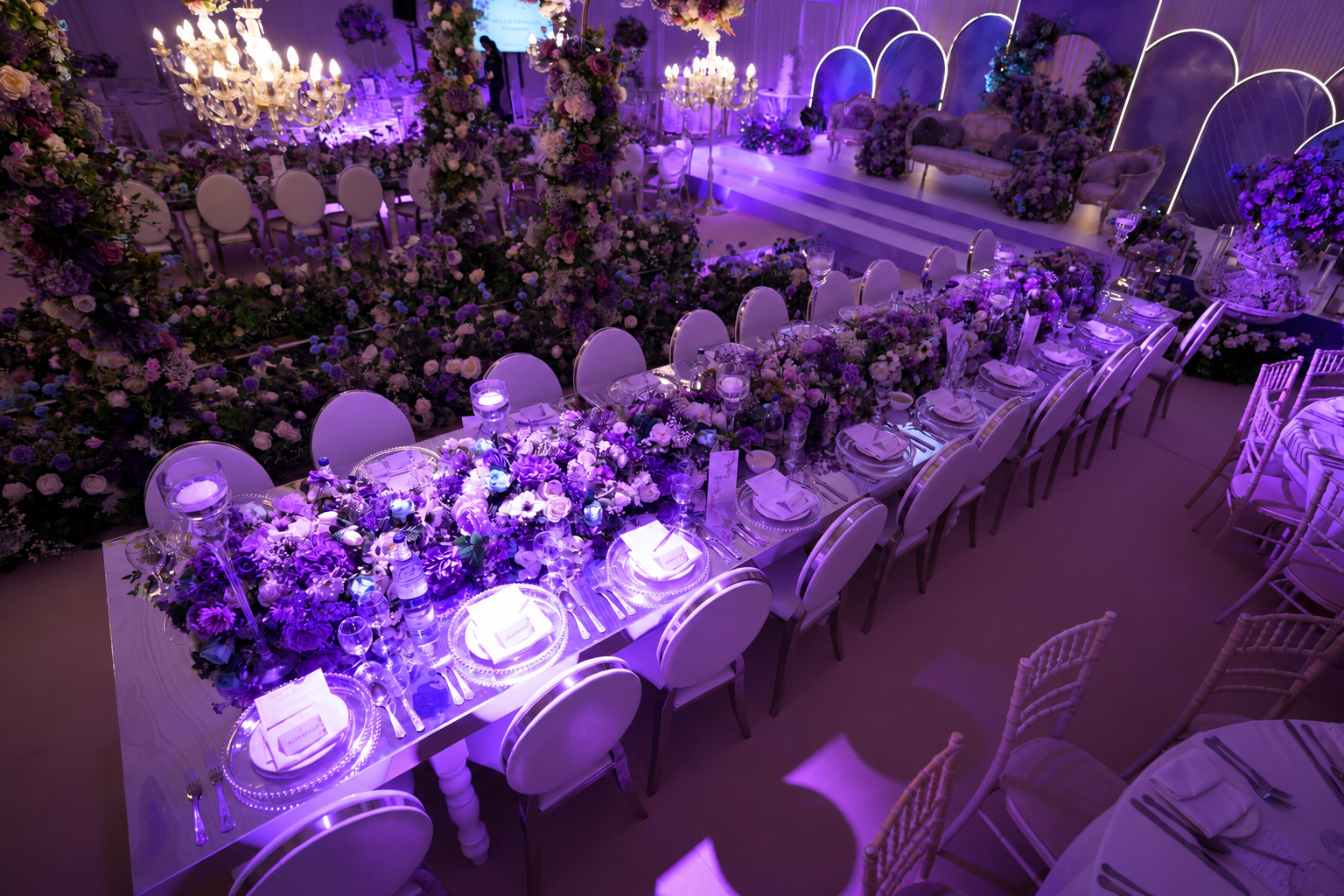Reception tables with pink floral arrangements and purple lighting