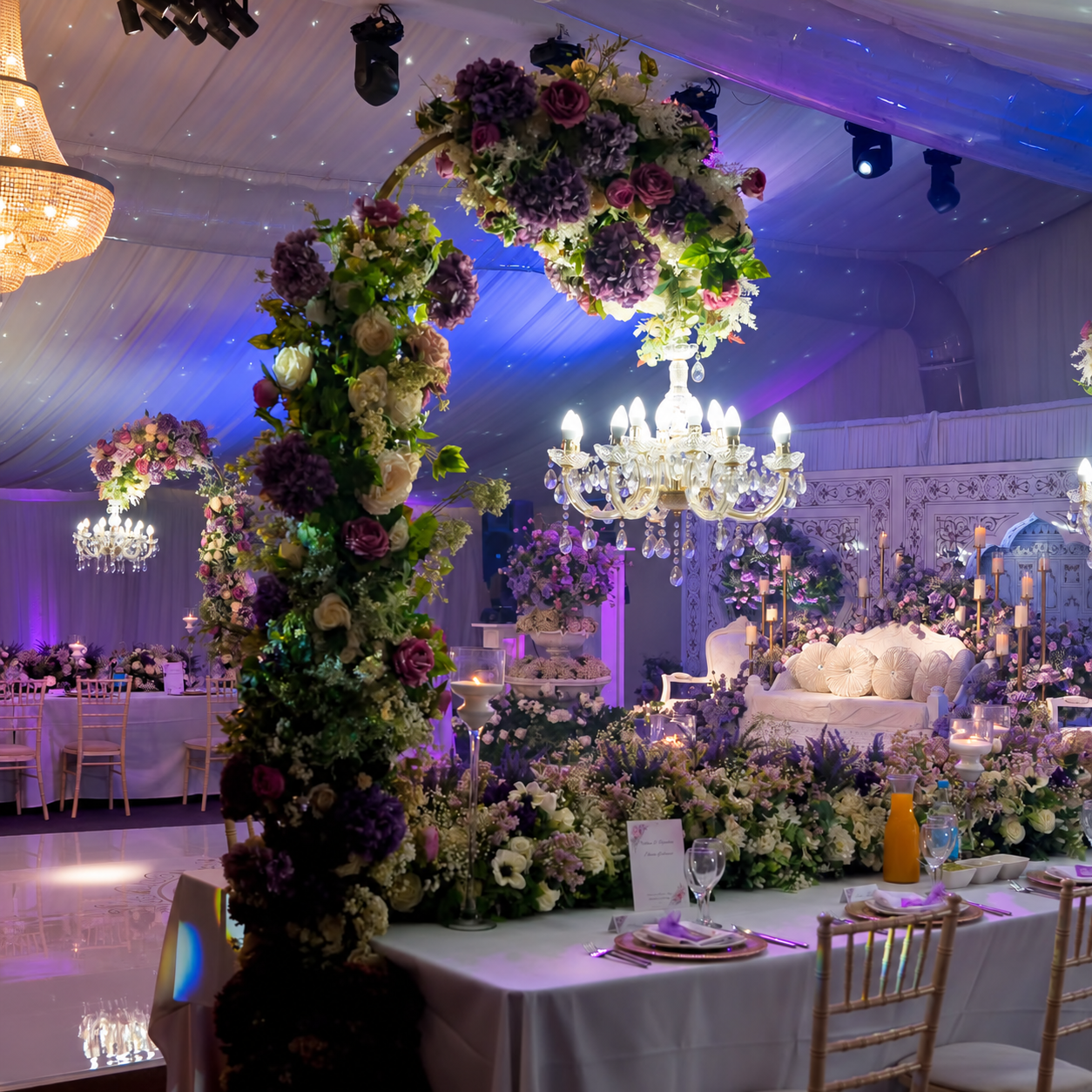 Floral arch and hanging chandelier beside the reception stage