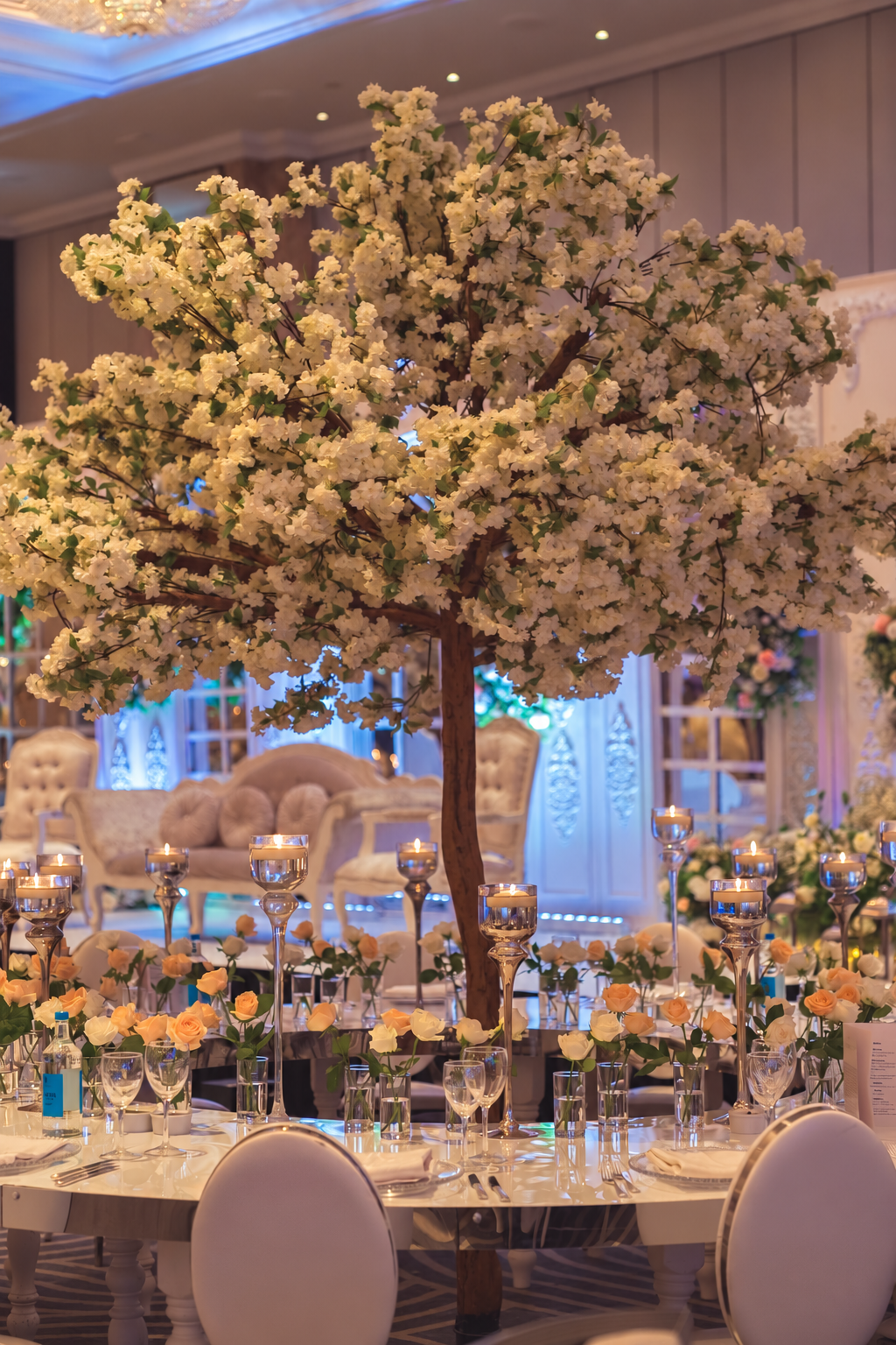 A tall floral centrepiece overlooking a wedding reception