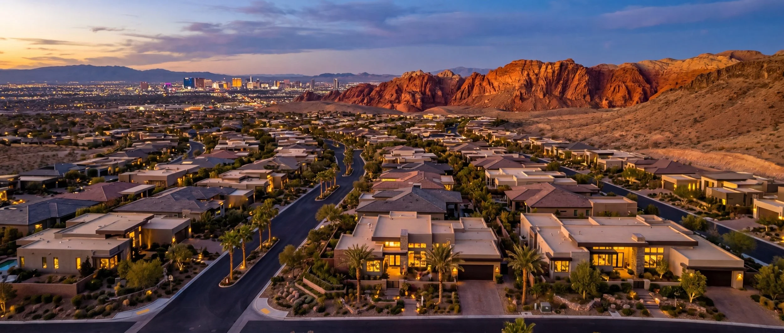 Aerial view of luxury homes in Summerlin South at dusk with Red Rock Canyon and Las Vegas Strip in the background
