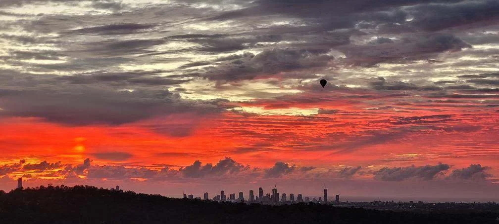 Hot air balloon above the Gold Coast skyline under a vivid sunrise