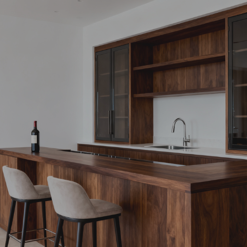 A beautiful cutom built wet bar. the wet bar is made of a dark mahogany. There are two barstools sitting in front of the bar and a bottle of wine sits on the end of the bar.